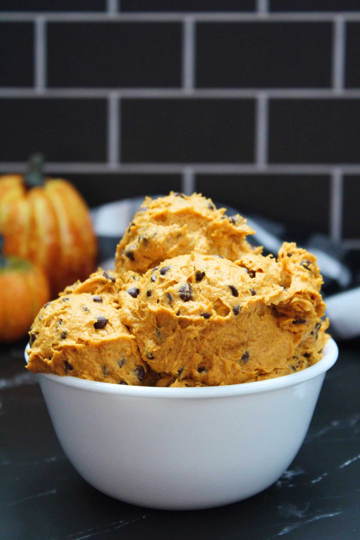 Scoops of orange edible pumpkin cookie dough in a bowl.