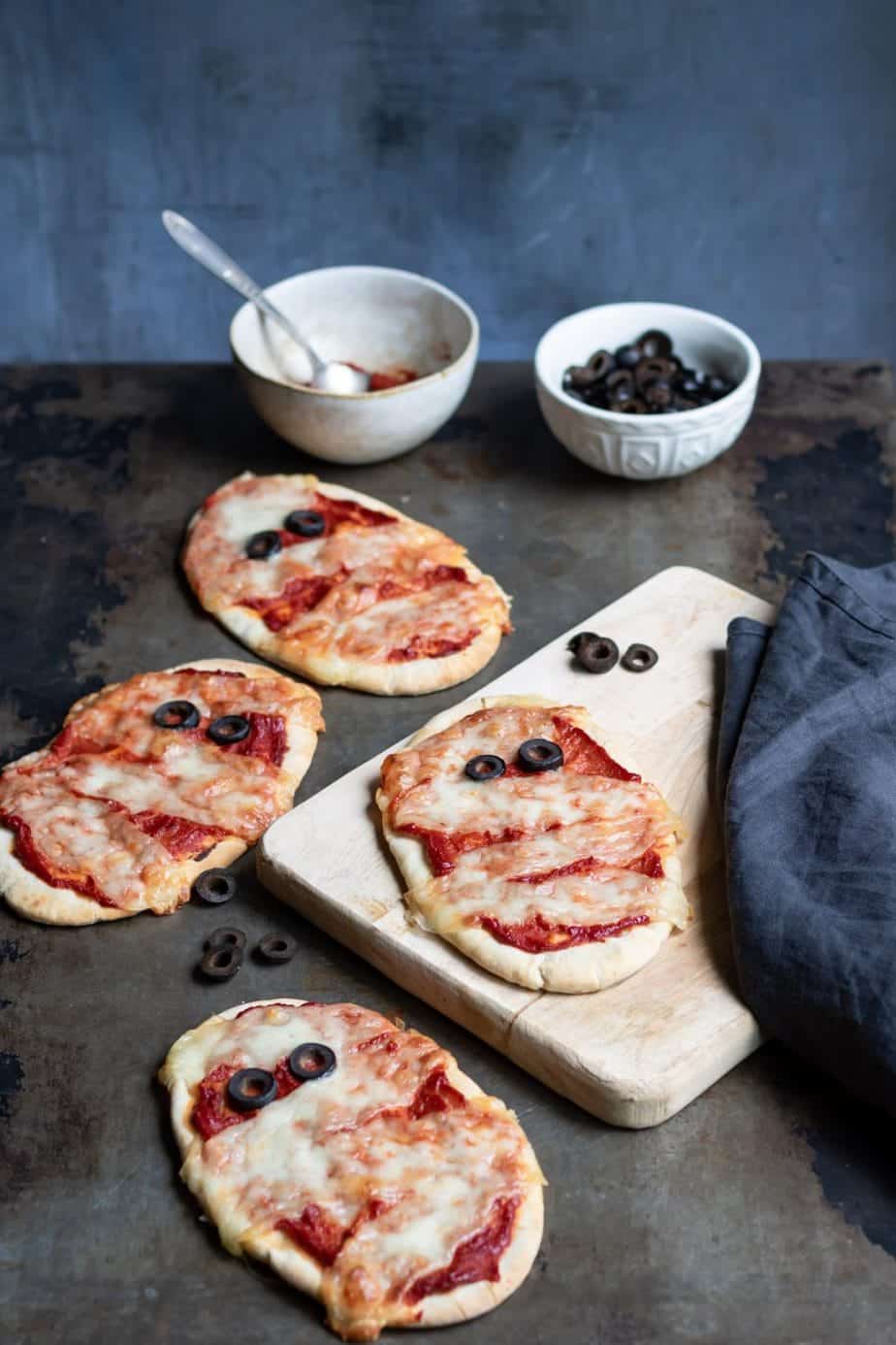 Mummy Halloween pizzas. The cheese gives the appearance of bandages and there are olives for eyes.