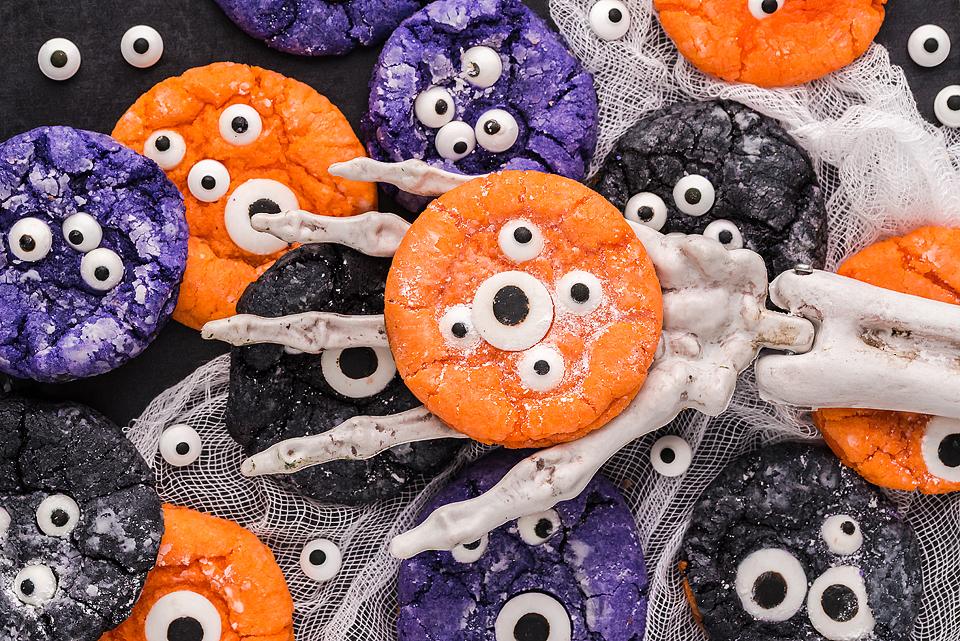 Monster eye crinkle cookies, held in a skeleton hand.