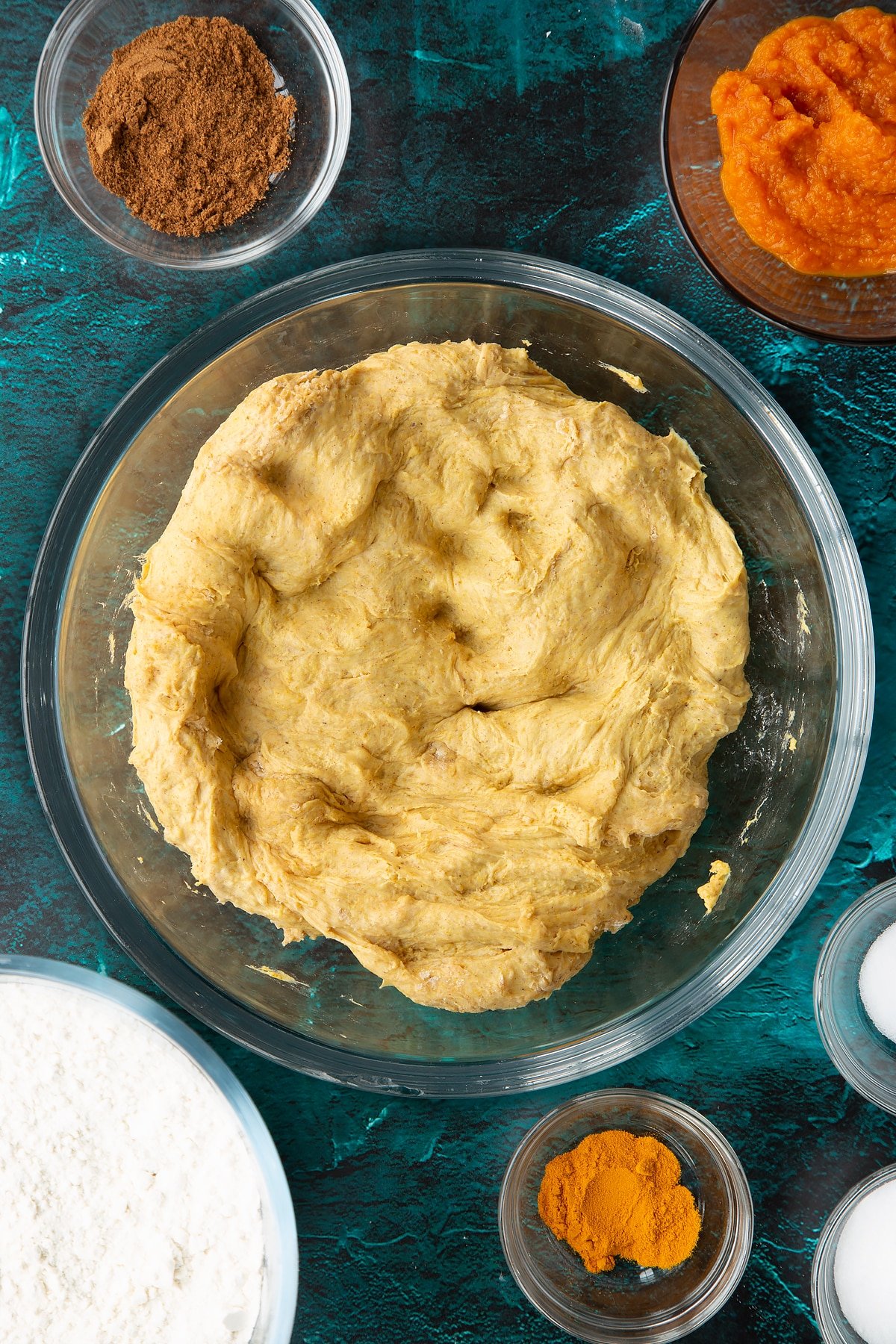 Pumpkin sourdough pressed into the base of a bowl. Ingredients to make pumpkin sourdough bread surround the bowl.