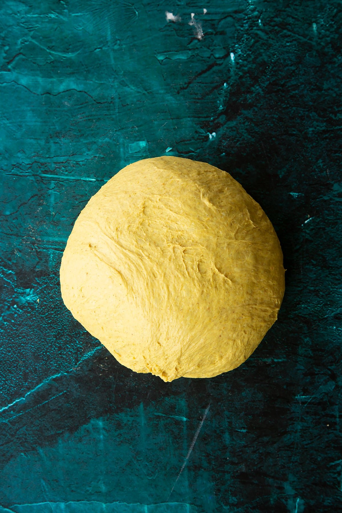 Risen pumpkin sourdough formed into a rough ball onto a clean surface.