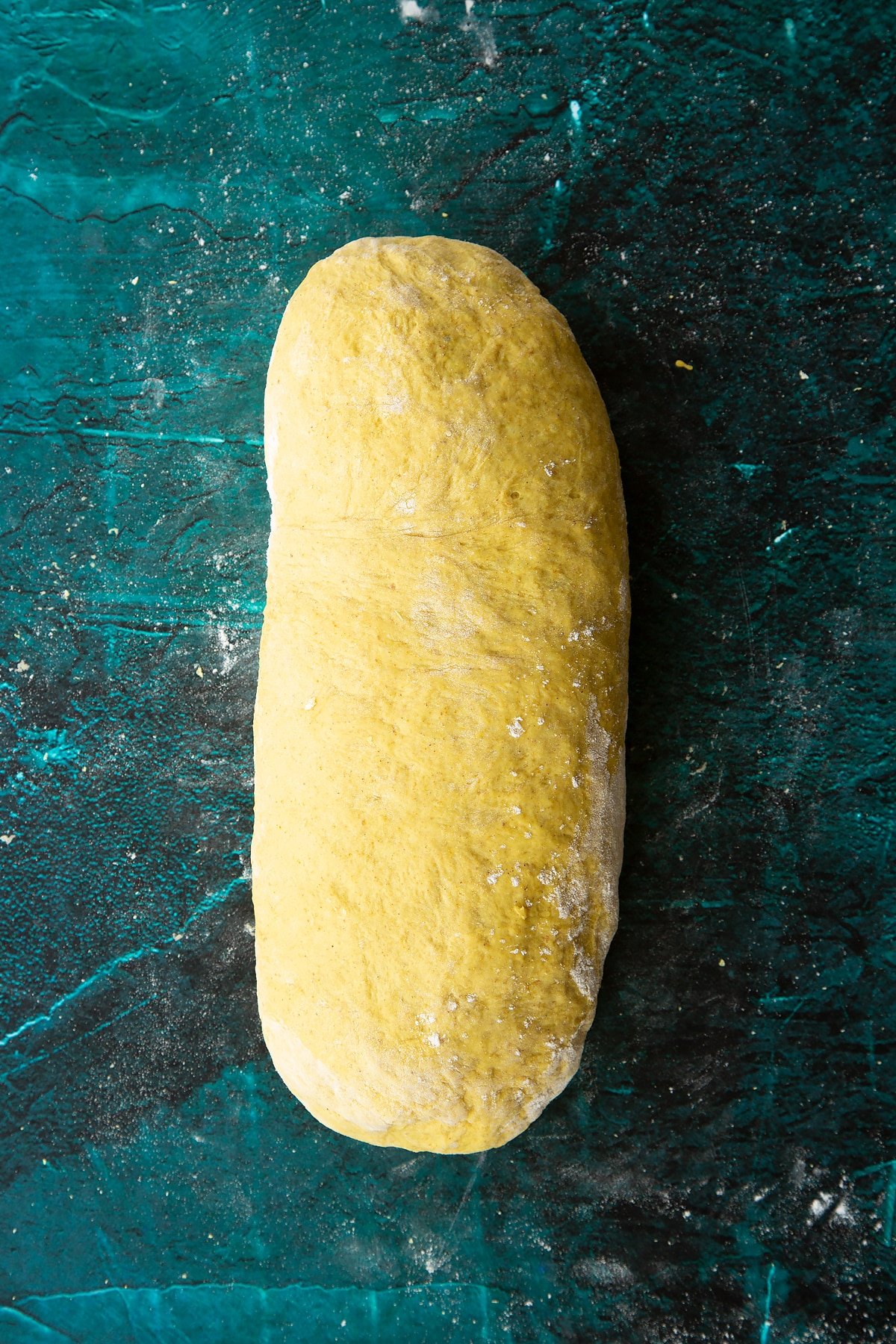 Pumpkin sourdough shaped into a sausage shape with a taut surface.