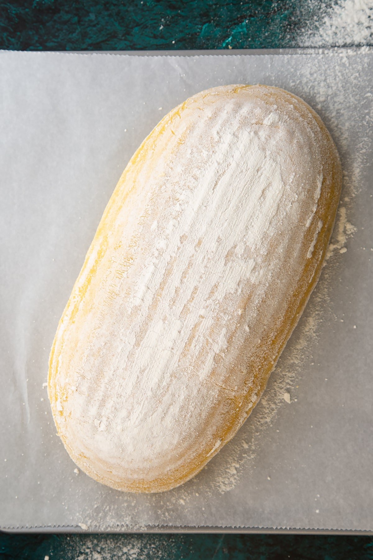 Shaped and risen pumpkin sourdough tipped out onto a baking sheet lined with baking paper.