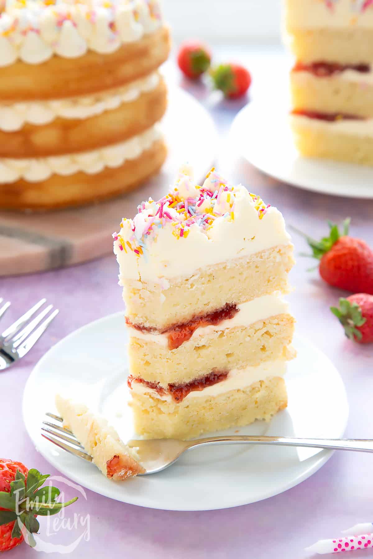Slice of vegan birthday cake on a small white plate. Some has been cut with a fork.