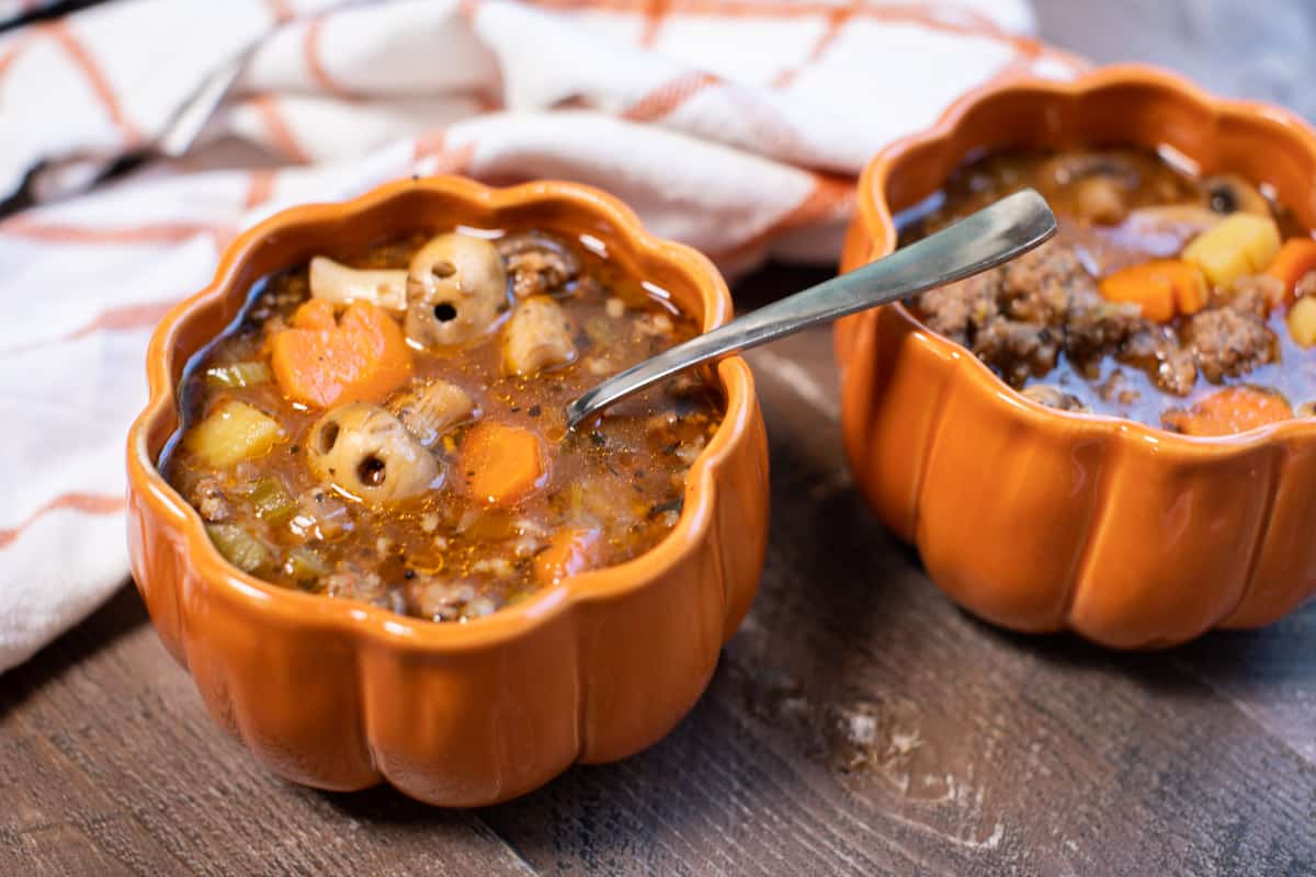 Witch's brew stew with mushroom skulls, served into two pumpkin shaped bowls.