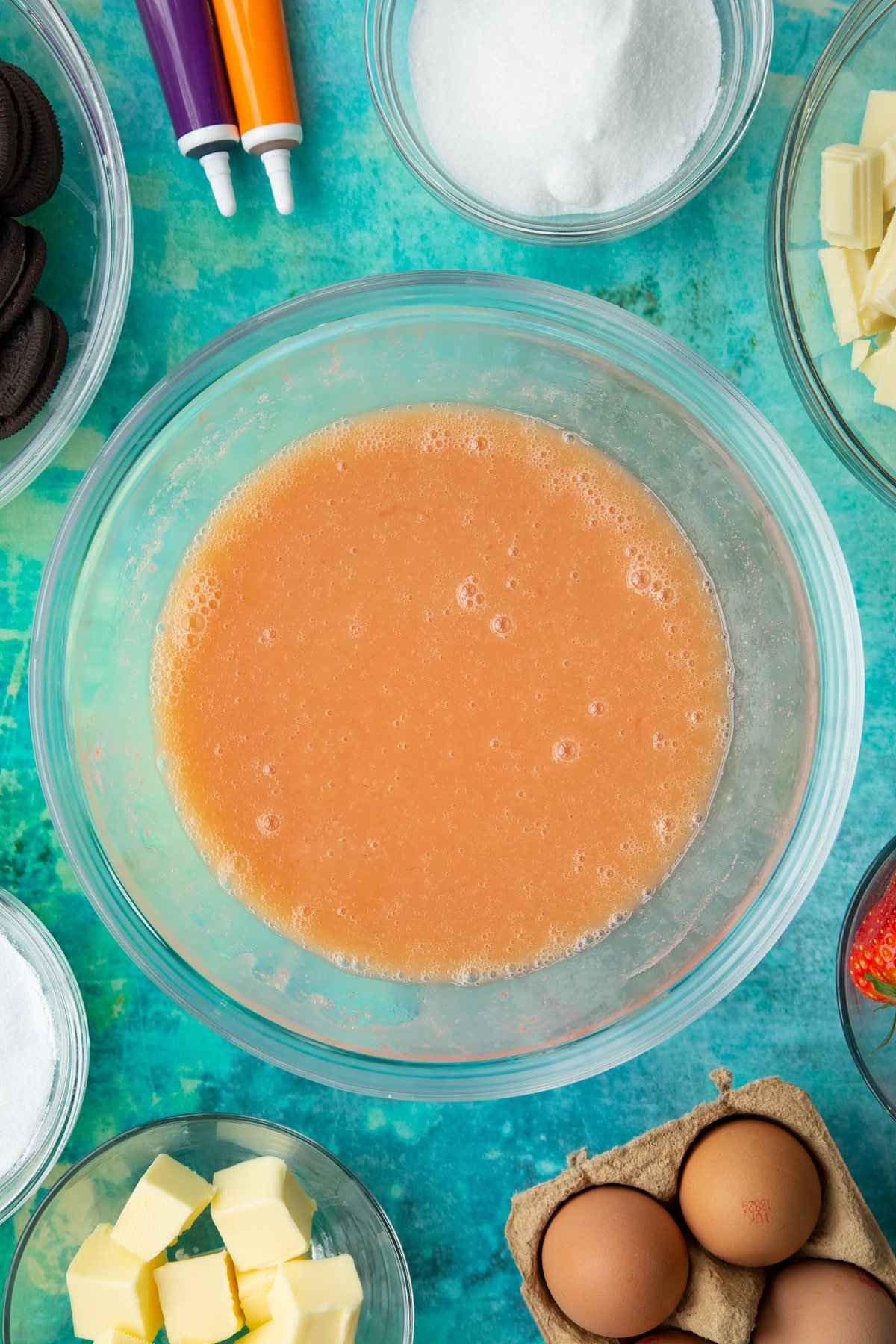 Strawberry curd ingredients in a bowl. Ingredients to make Halloween cheesecake surround the bowl.