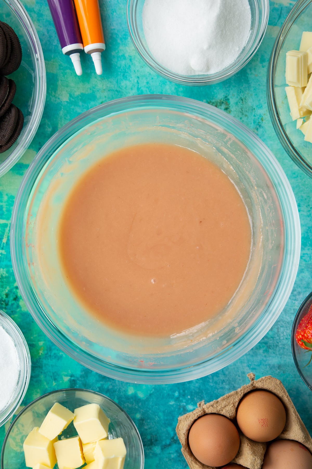 Strawberry curd in a bowl. Ingredients to make Halloween cheesecake surround the bowl.