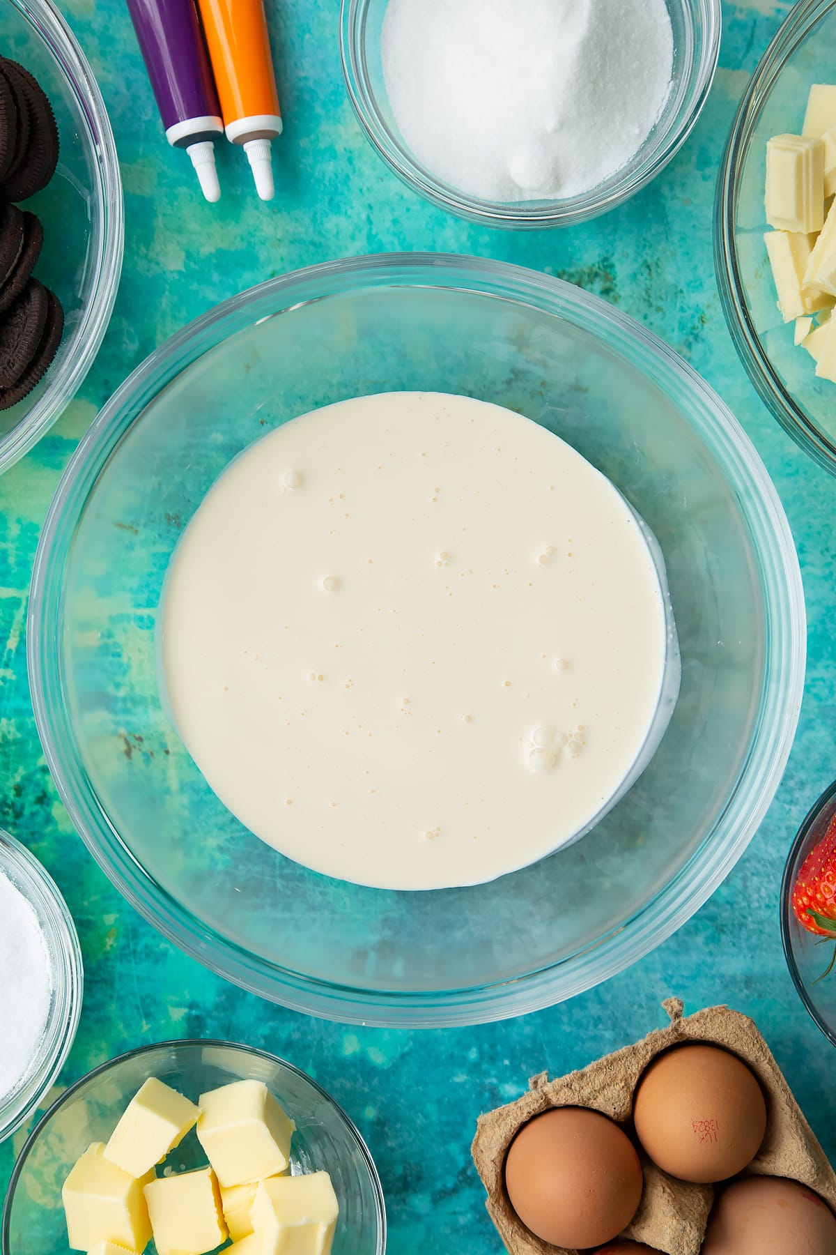 Double cream in a bowl. Ingredients to make Halloween cheesecake surround the bowl.