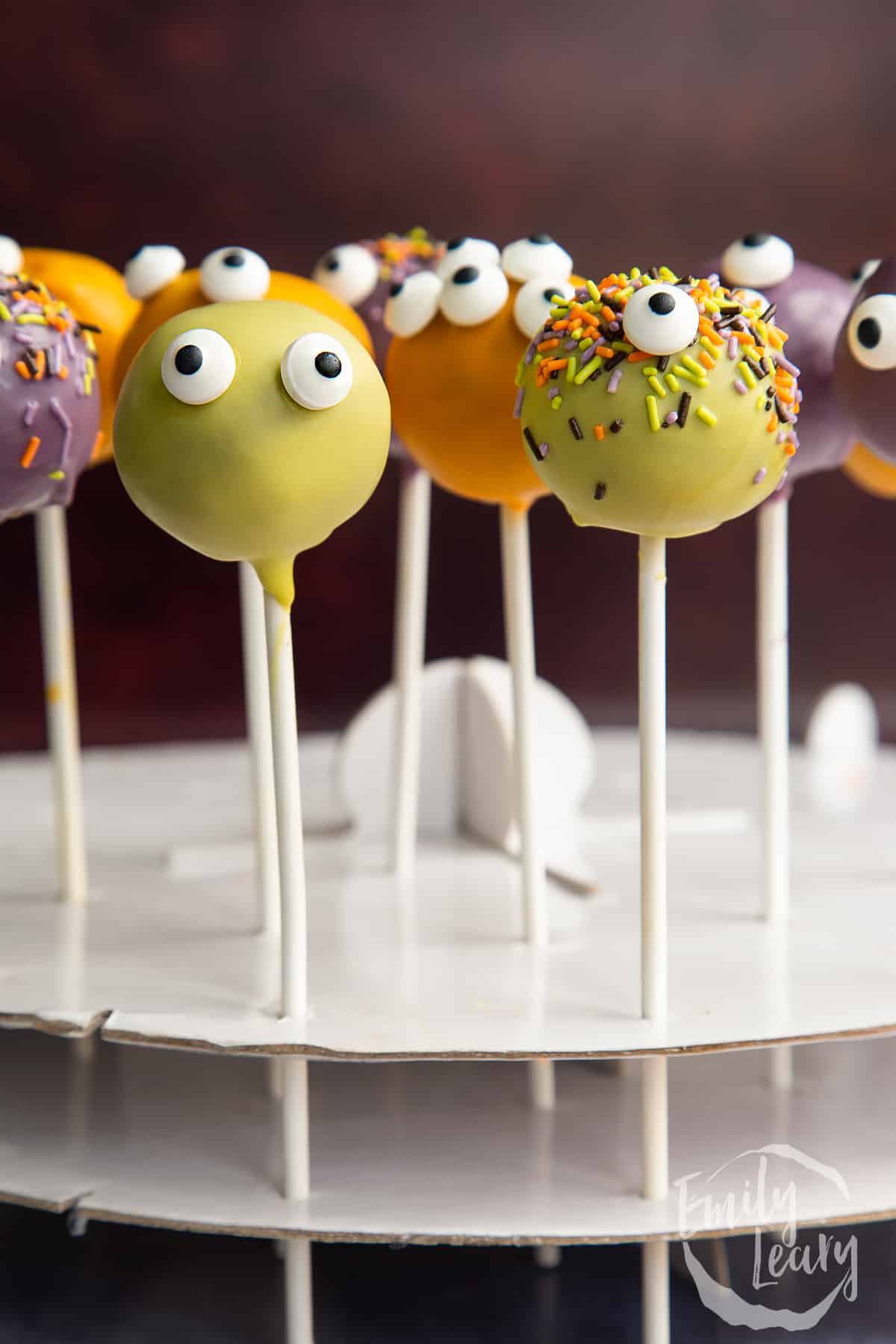 Halloween cake pops standing in a white cardboard cake pop stand.