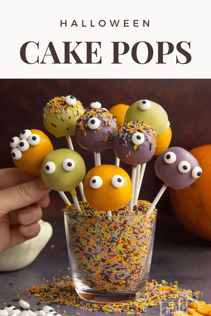 Halloween cake pops standing in a glass filled with Halloween sprinkles. A hand reaches for one. Caption reads: Halloween cake pops.