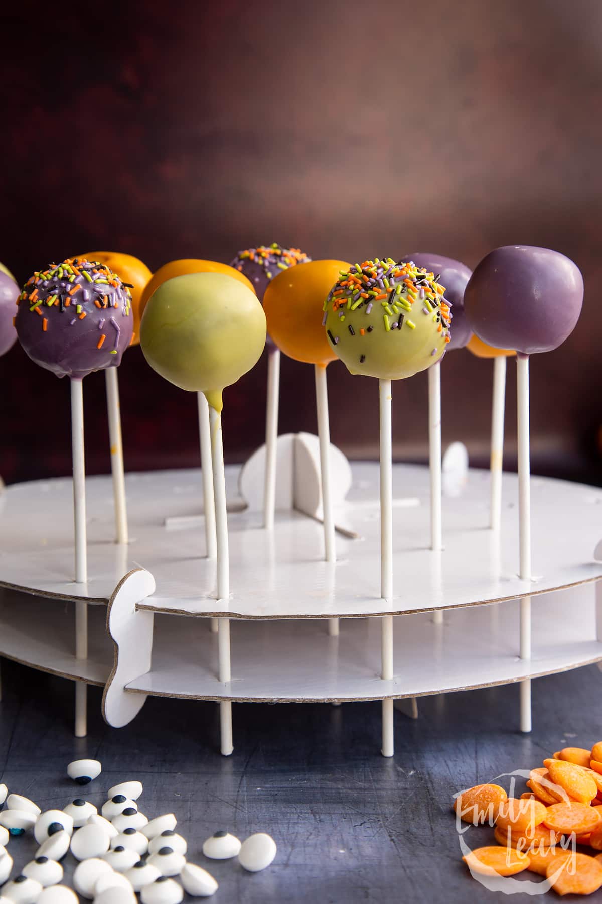 Halloween cake pops standing in white cardboard, ready to finish decorating.