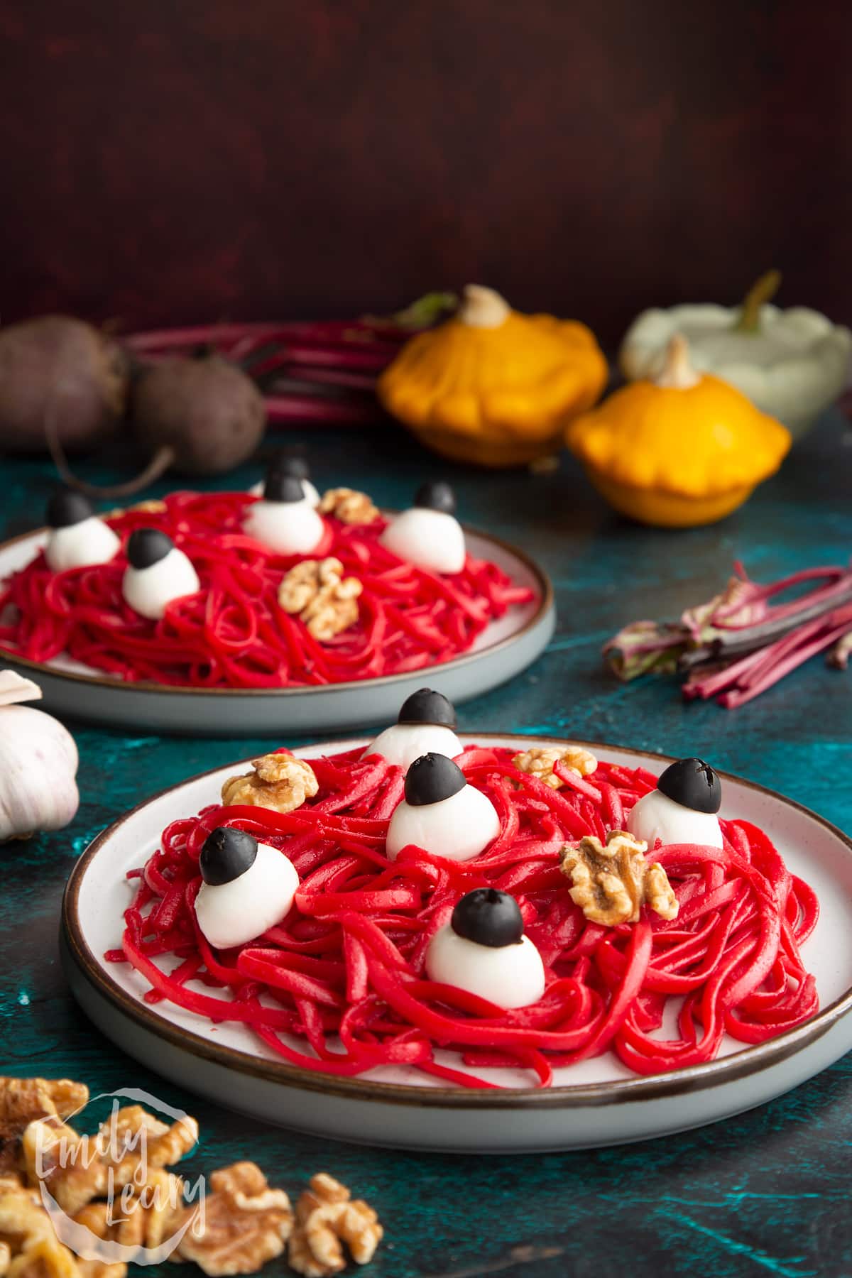 A plate with a beetroot Halloween pasta recipe, topped with mozzarella eyes and walnut brains.