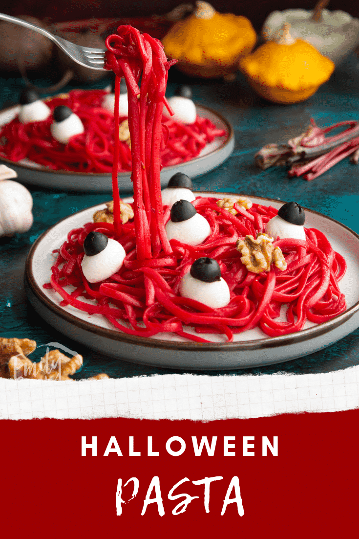 Two plates with a beetroot Halloween pasta recipe, topped with mozzarella eyes and walnut brains. A fork lifts some pasta. Caption reads: Halloween pasta.