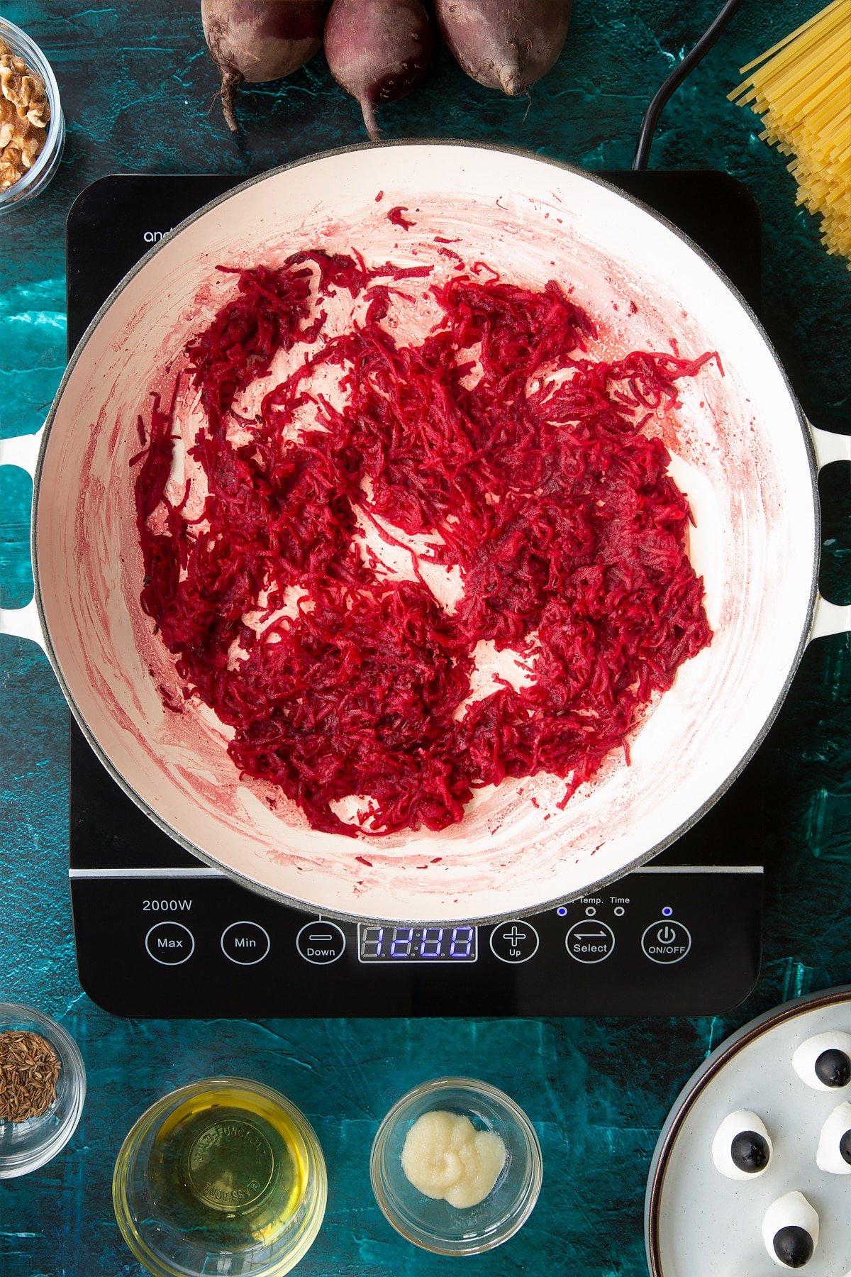 Sweated beetroot in a pan. Ingredients to make a Halloween pasta recipe surround the pan.