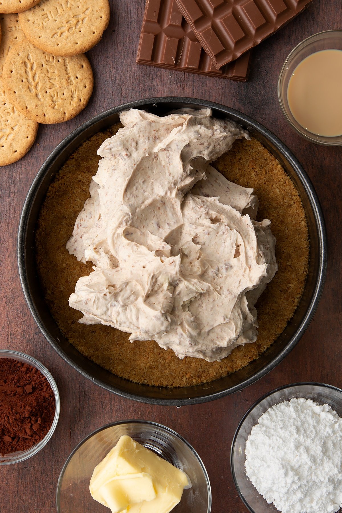Baileys cheesecake filling spooned on top of a biscuit base in a cake tin,