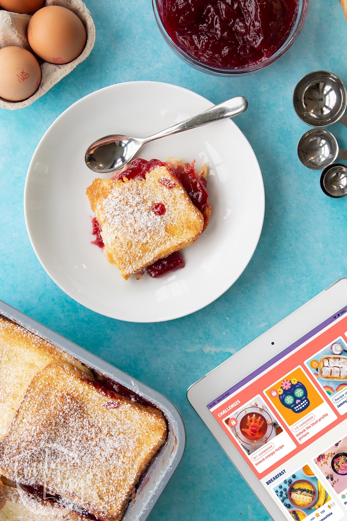 Finished bowl of Bread and butter pudding with jam with a spoon on the side.