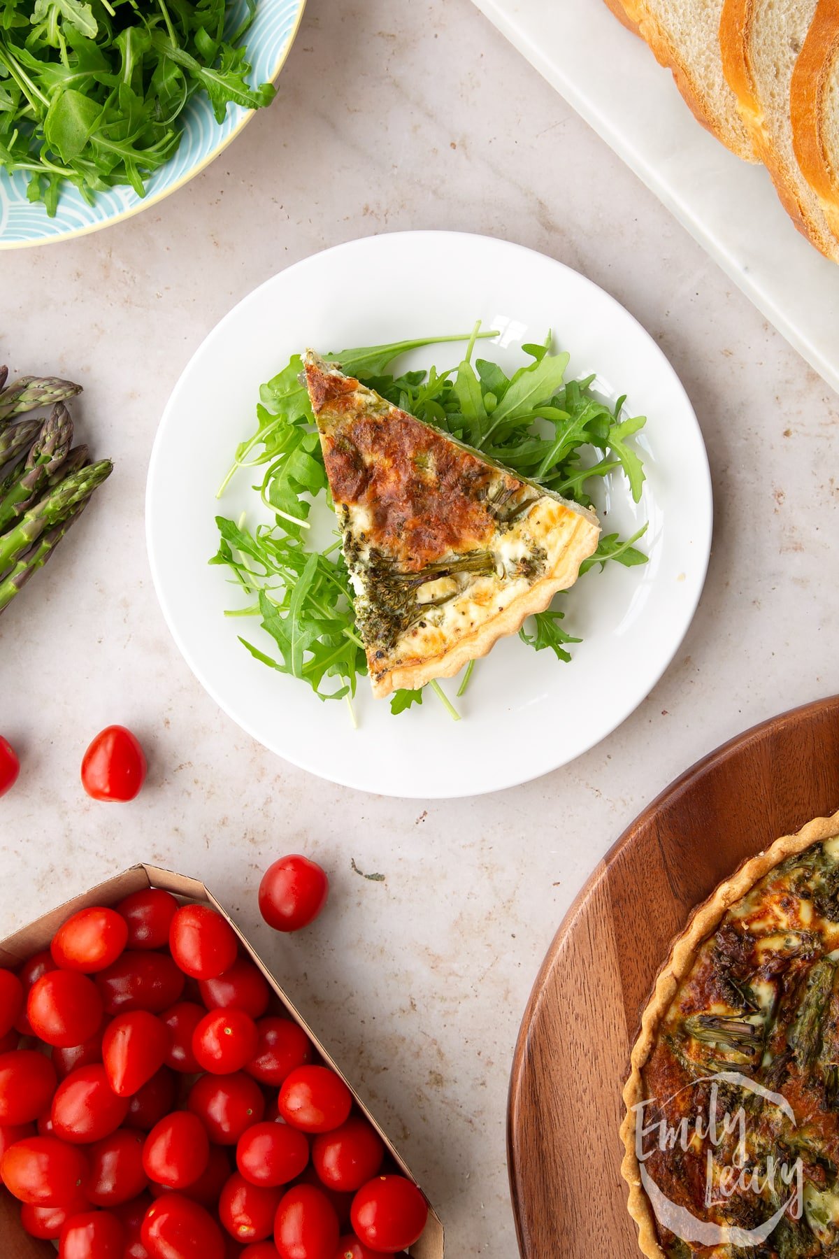 Overhead shot of a slice of broccoli and asparagus quiche served on a bed of salad.