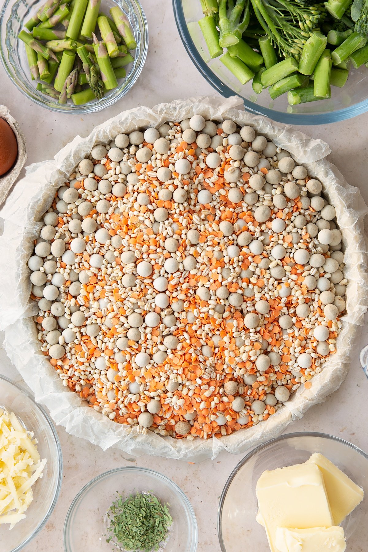 Overhead shot of the pastry inside the pie tin being worked in with baking beans. 