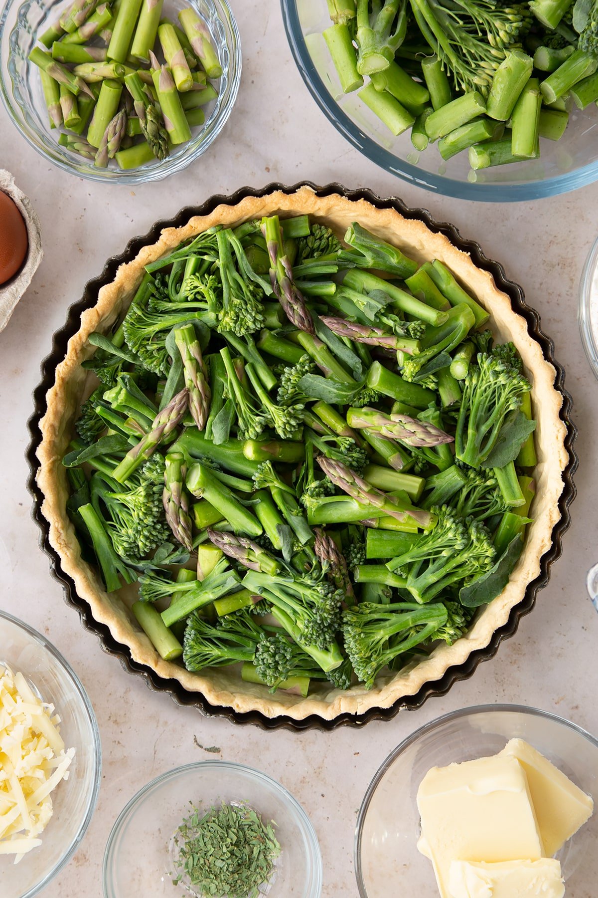 Overhead shot of adding the asaparagus, brocoli and beans to the pastry tin. 