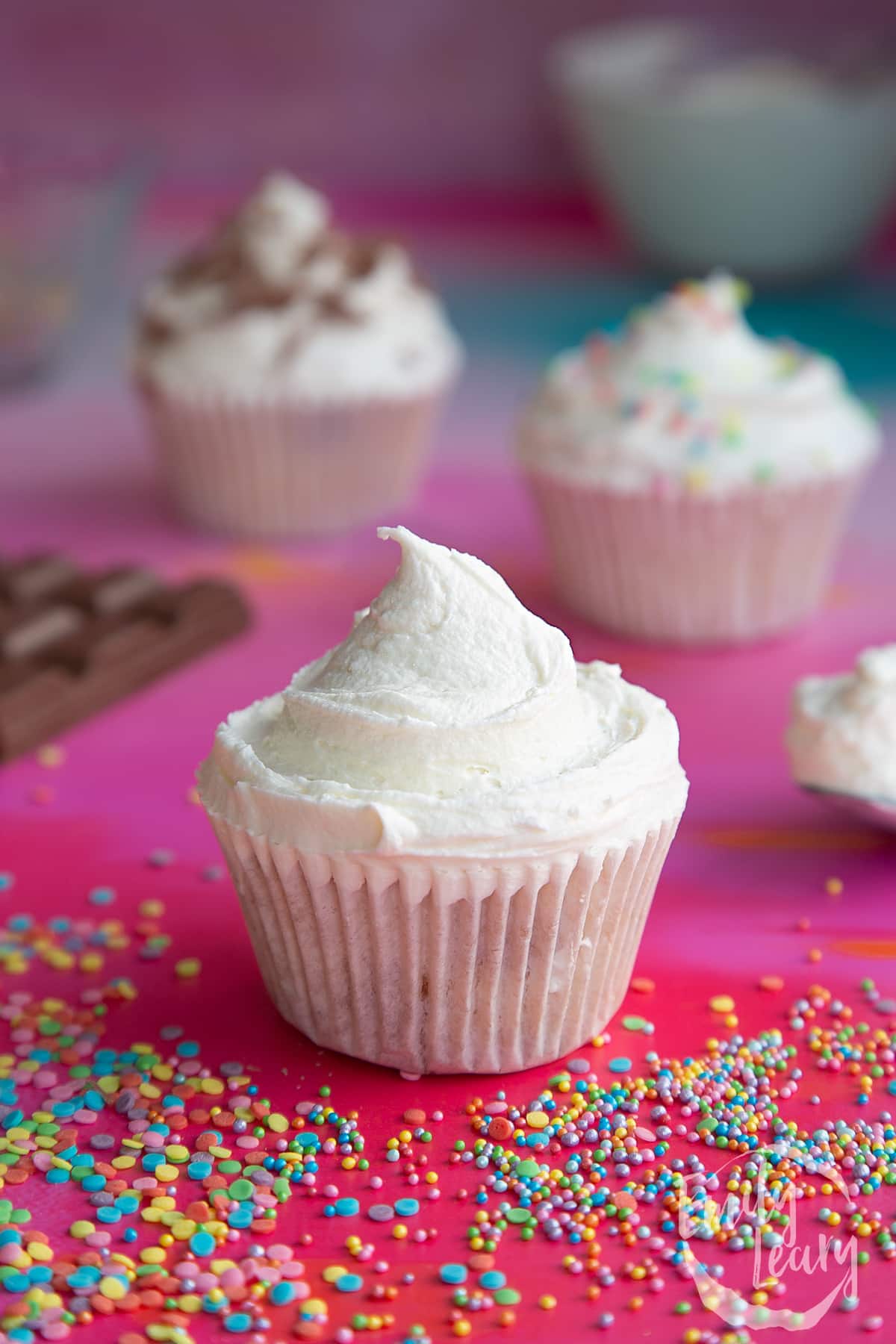 a side view of a plain sponge cupcake with a swirl of white fosting on top.