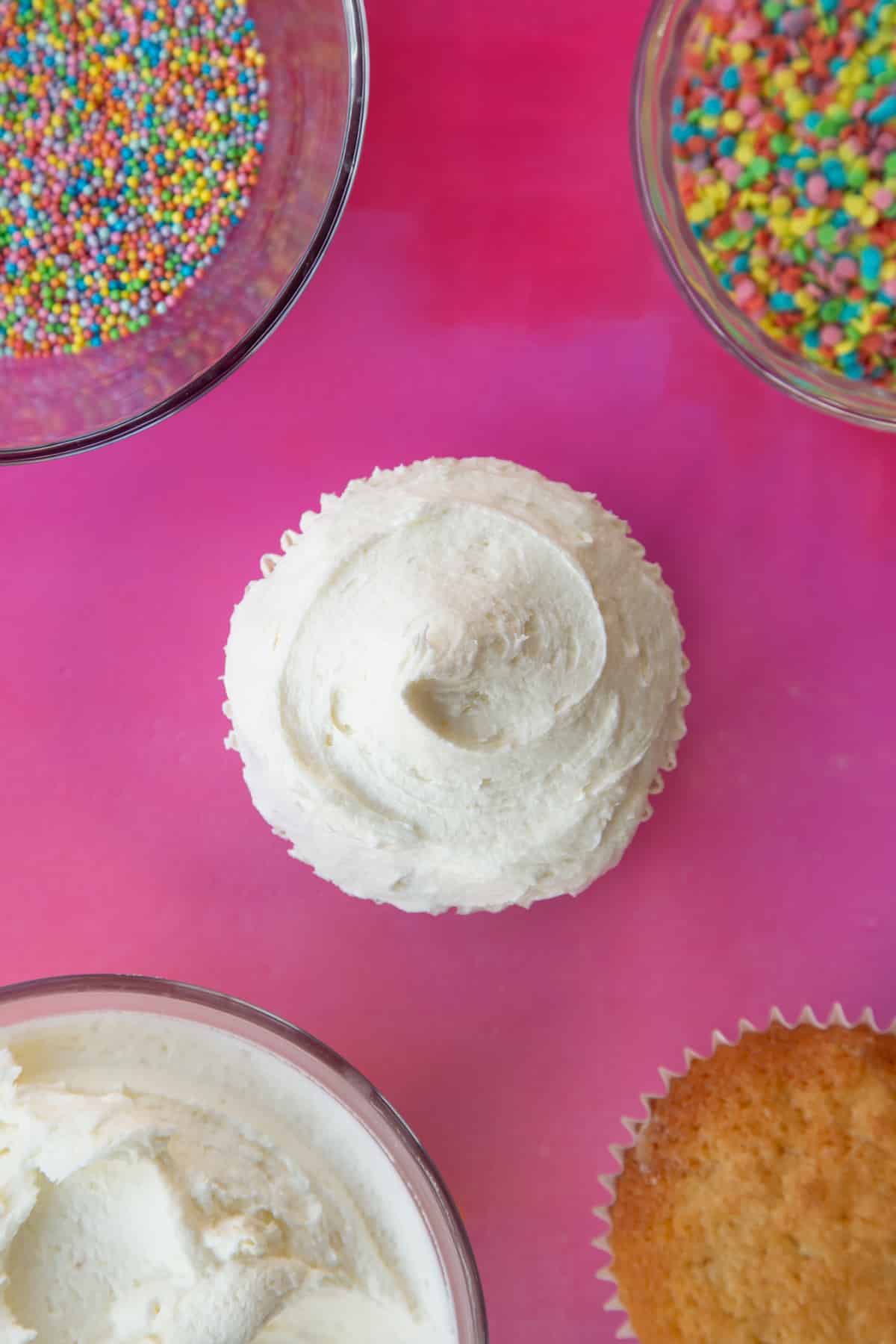 an over head view of a plain sponge cupcake with a swirl of white fosting on top.
