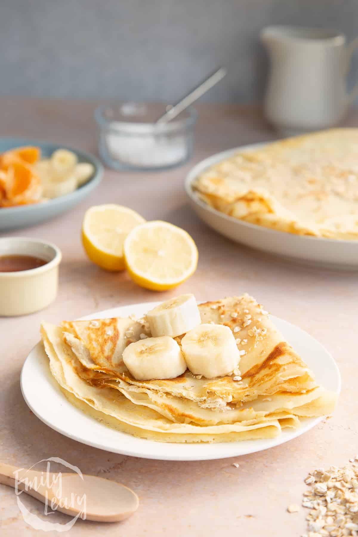Gluten free crepe on a white plate. It is folded and topped with bananas.