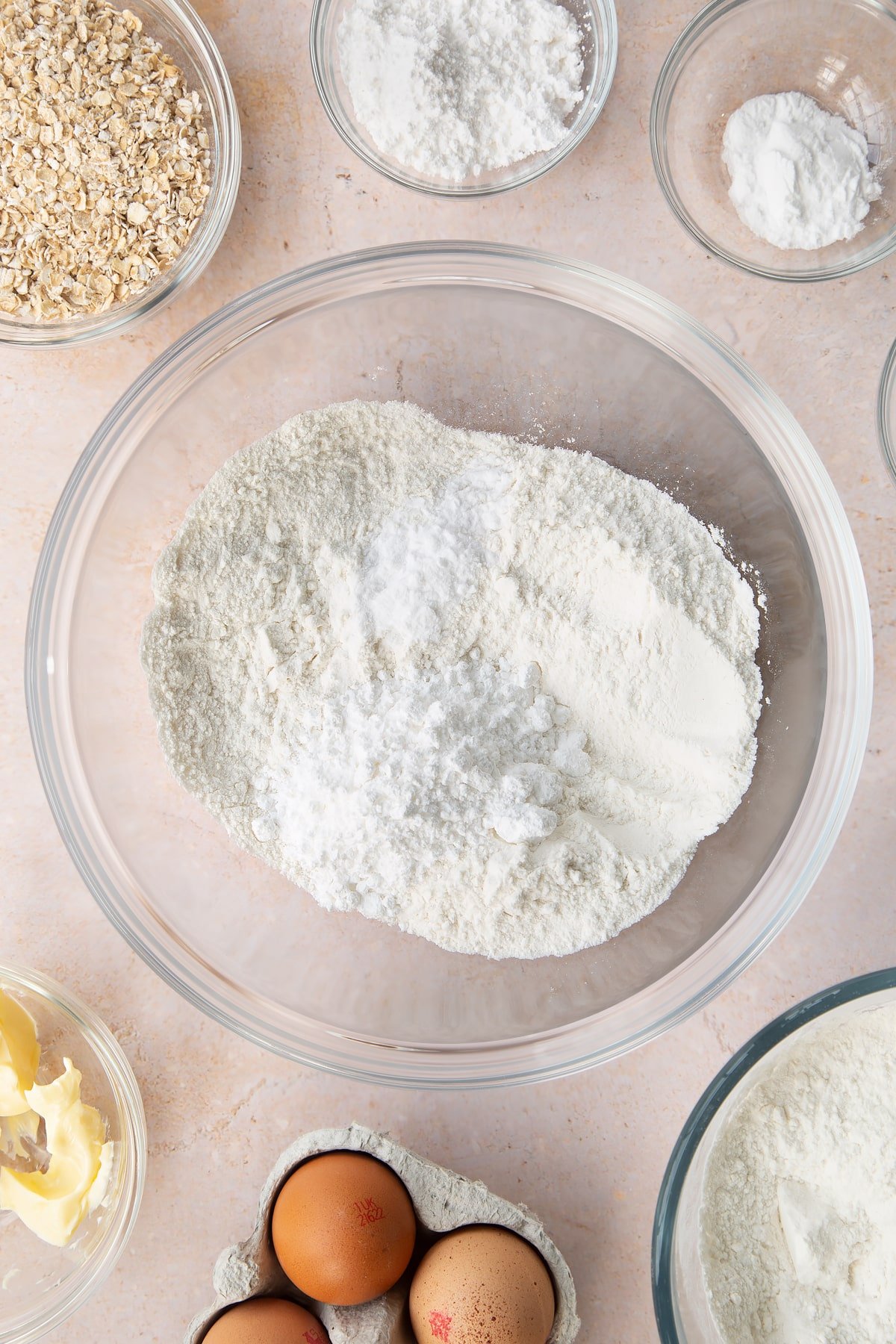 Flour, salt, bicarbonate of soda and icing sugar in a bowl. Ingredients to make gluten free crepes surround the bowl.