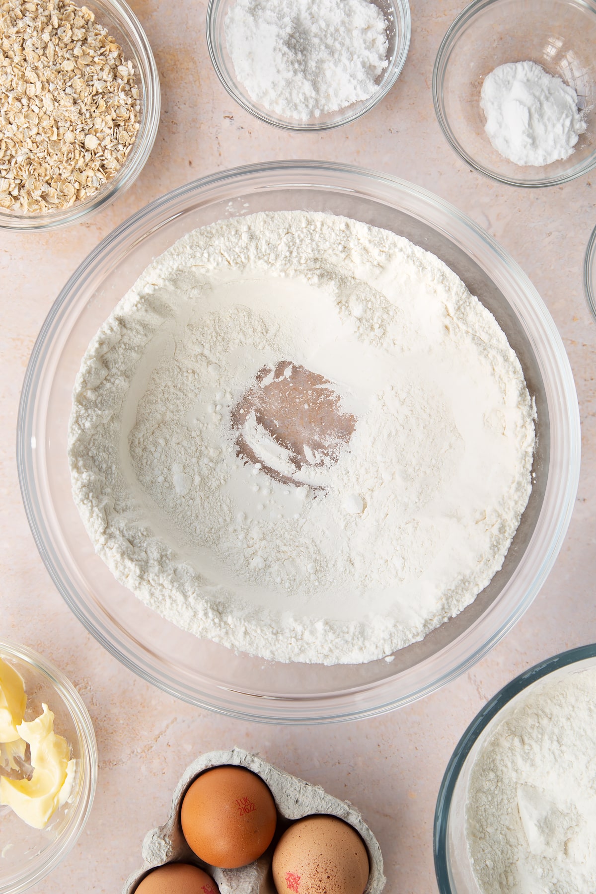 Flour, salt, bicarbonate of soda and icing sugar in a bowl. They're mixed together with a well in the middle. Ingredients to make gluten free crepes surround the bowl.