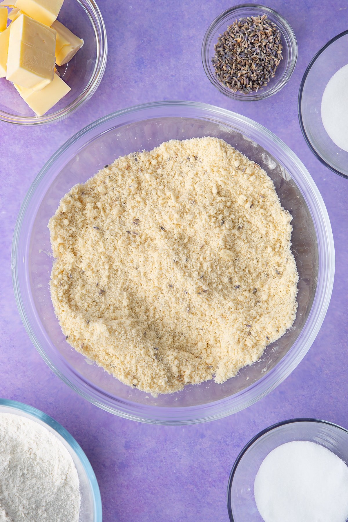 Flour, sugar, butter and lavender mixed to a crumb in a bowl. Ingredients to make lavender shortbread cookies.