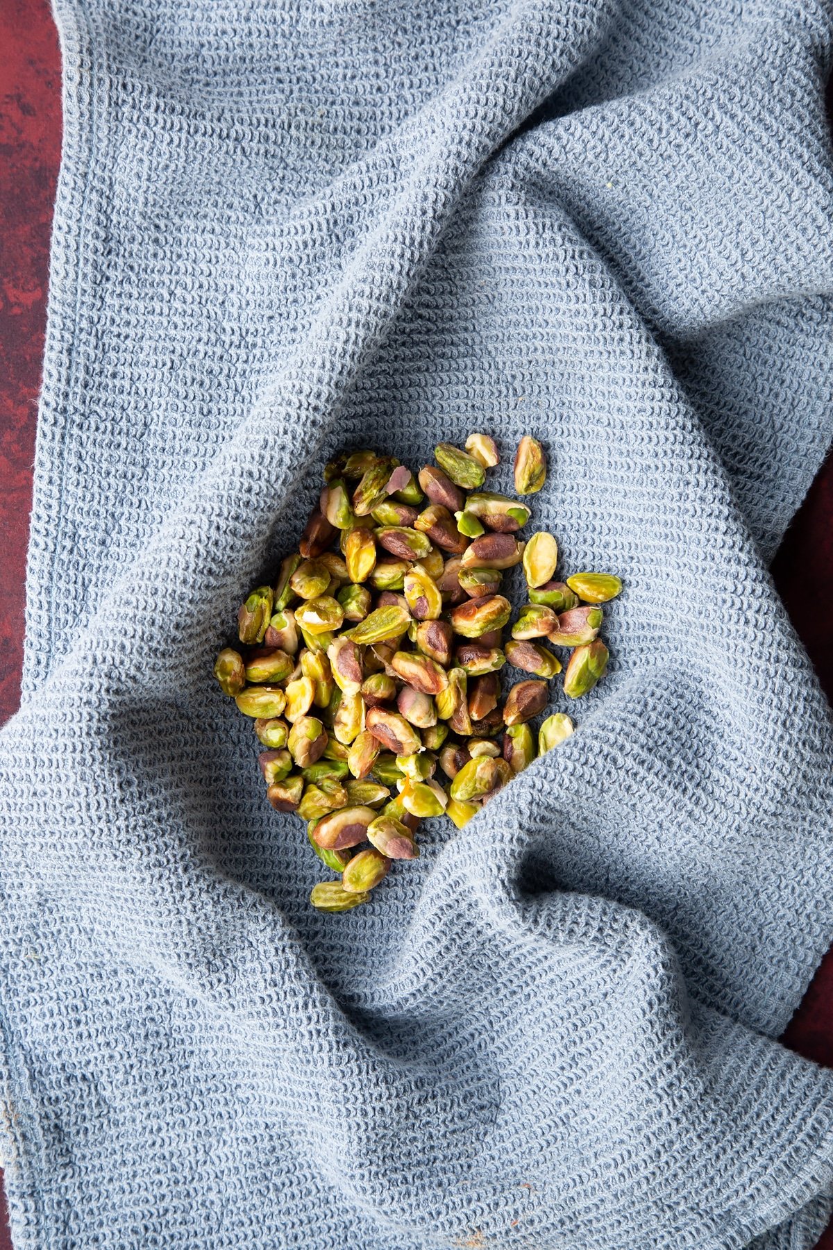 Overhead shot of a handful of pistachio on a towel.
