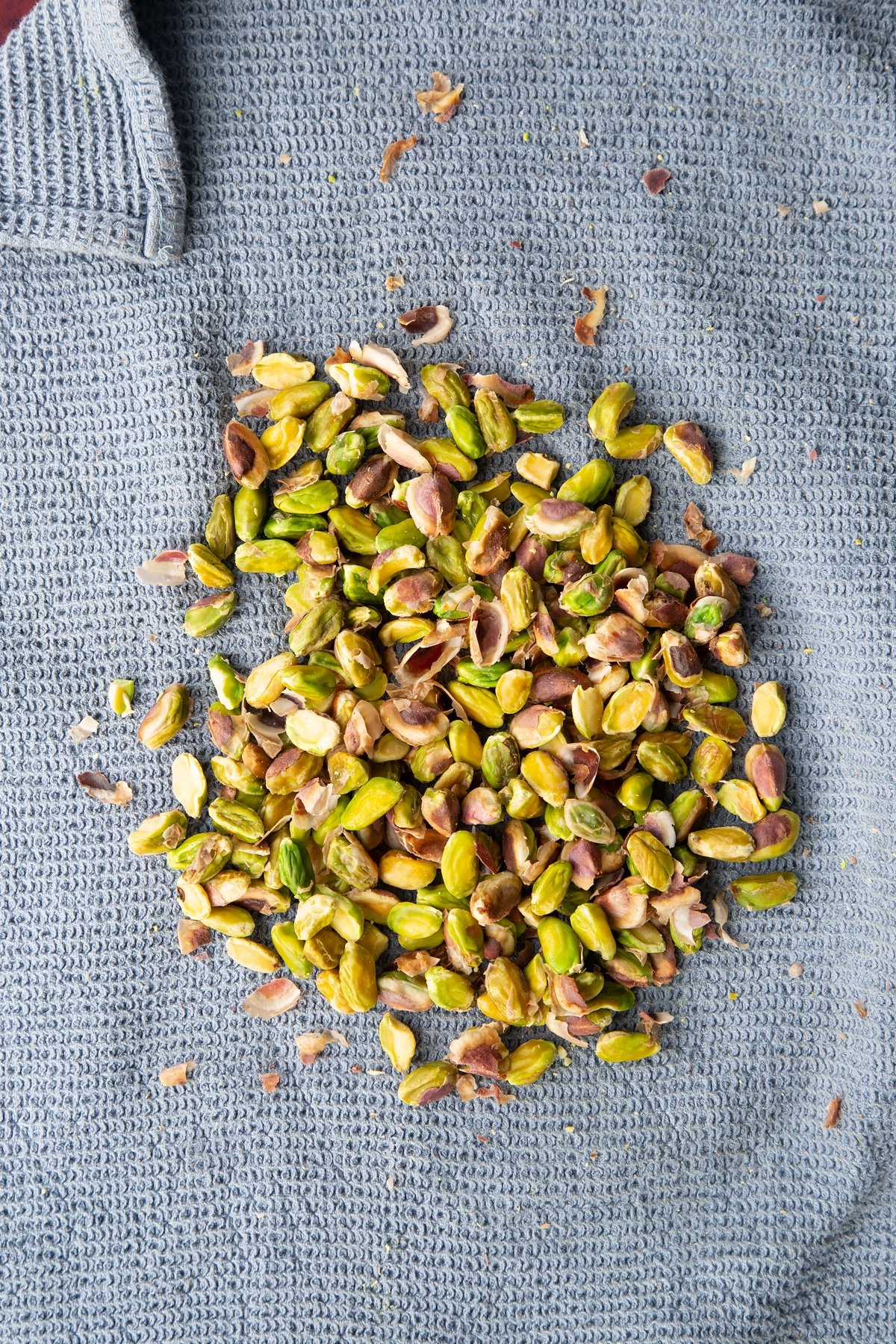 Overhead shot of the skins being released from the pistachio on a towel.