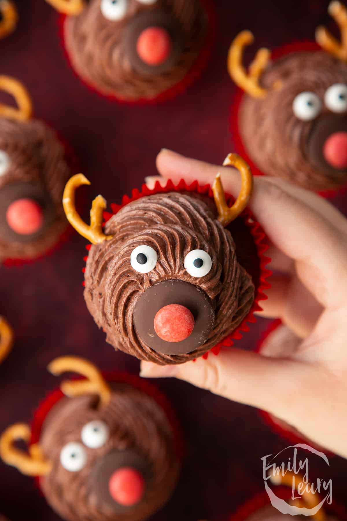 Hand holding a reindeer cupcakes shown from above.