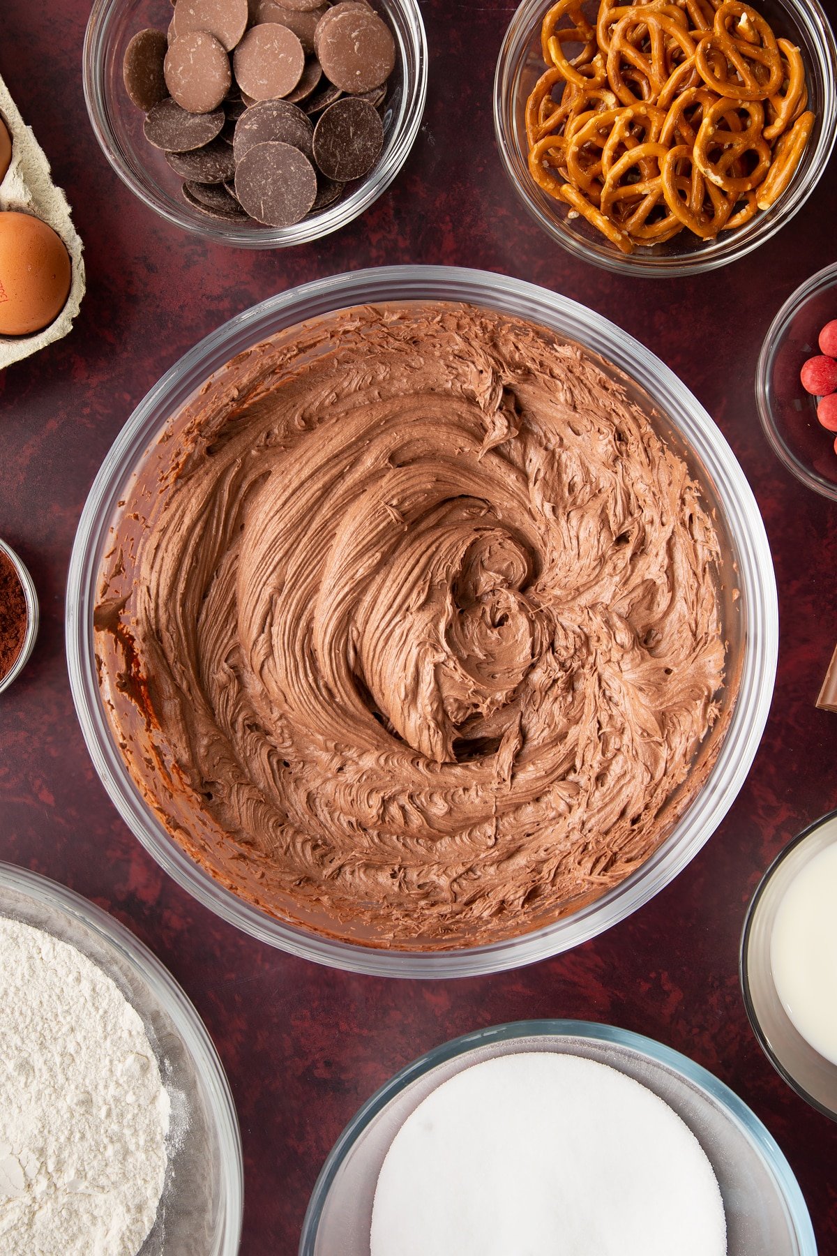 Chocolate frosting in a mixing bowl. Ingredients to make reindeer cupcakes surround the bowl.