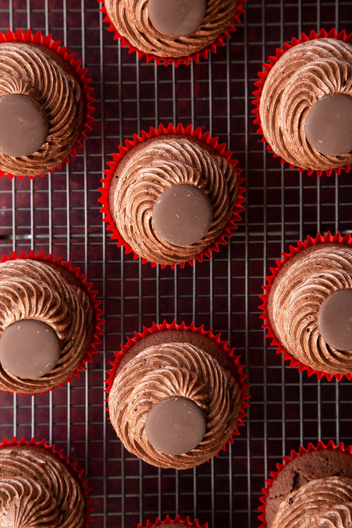 Reindeer cupcakes shown from above on a wire rack. They don't have eyes, noses or antlers yet.