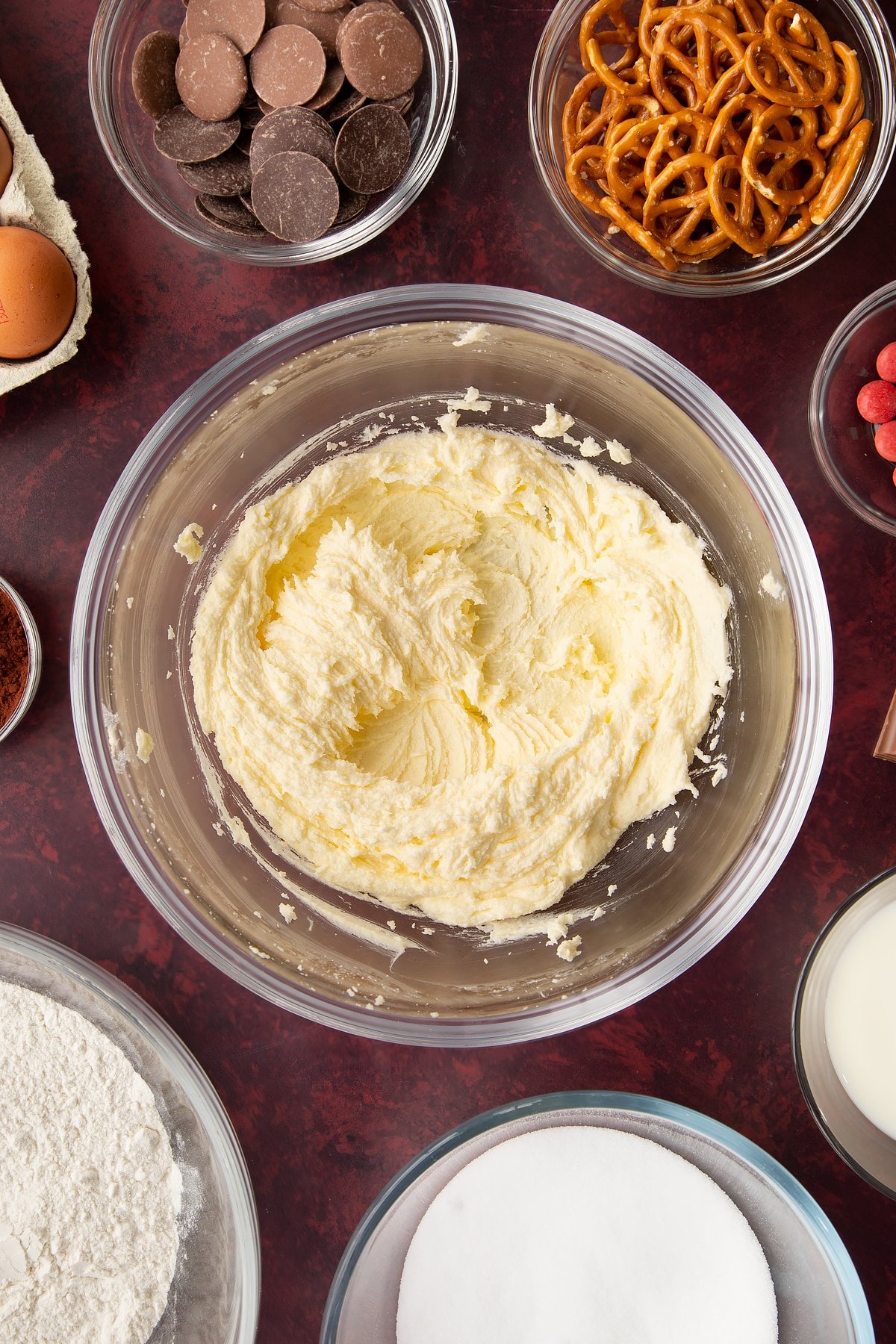 Softened butter and caster sugar beaten together in a mixing bowl. Ingredients to make reindeer cupcakes surround the bowl.