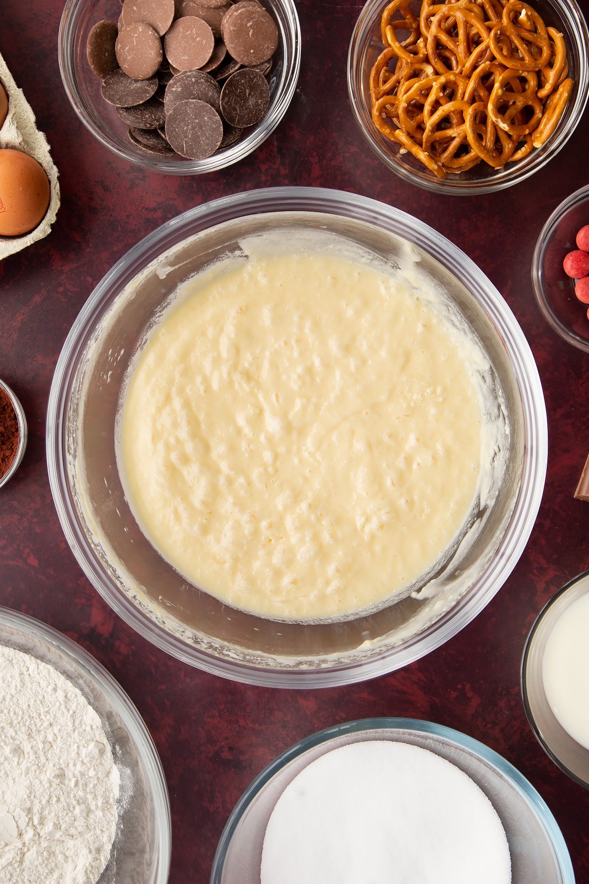 Softened butter, caster sugar, milk and eggs beaten together in a mixing bowl. Ingredients to make reindeer cupcakes surround the bowl.