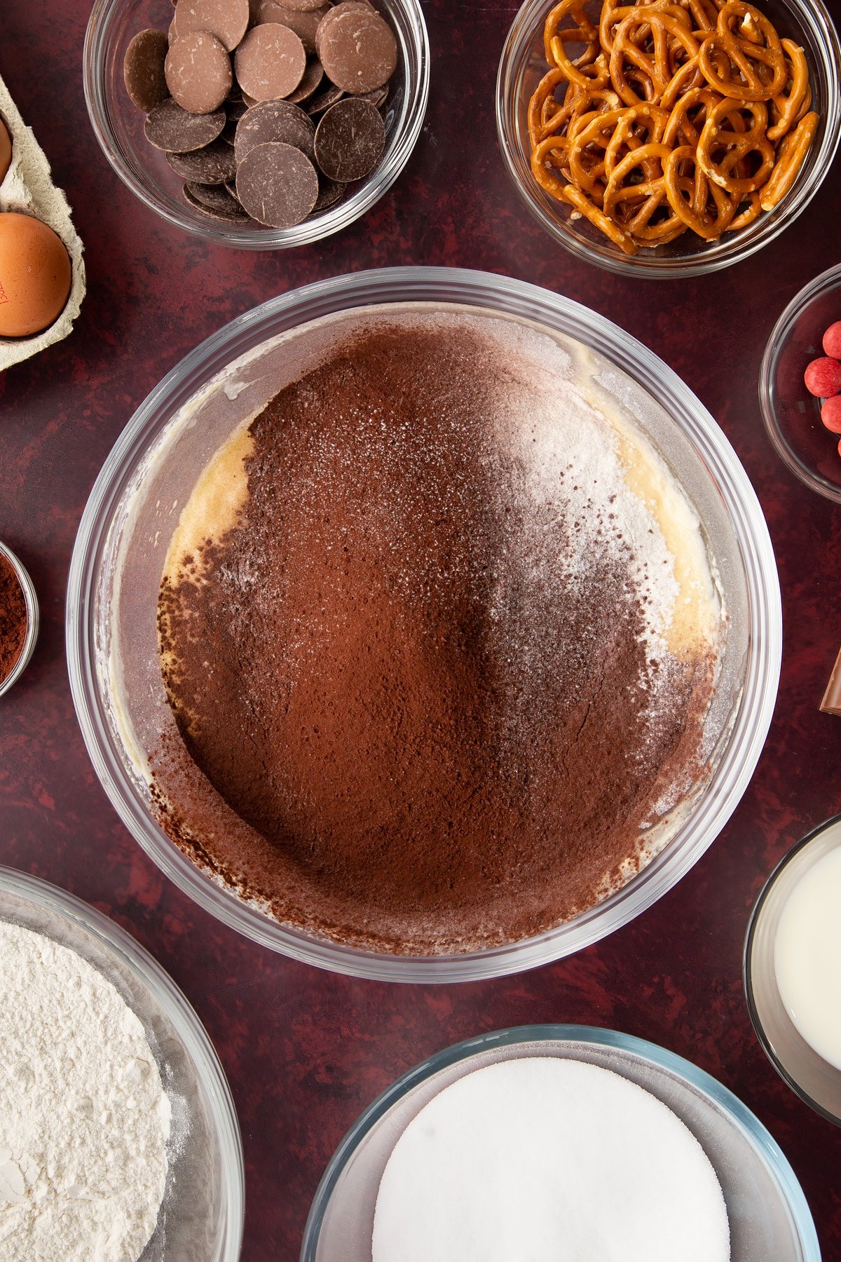 Softened butter, caster sugar, milk and eggs beaten together in a mixing bowl with cocoa and flour on top. Ingredients to make reindeer cupcakes surround the bowl.