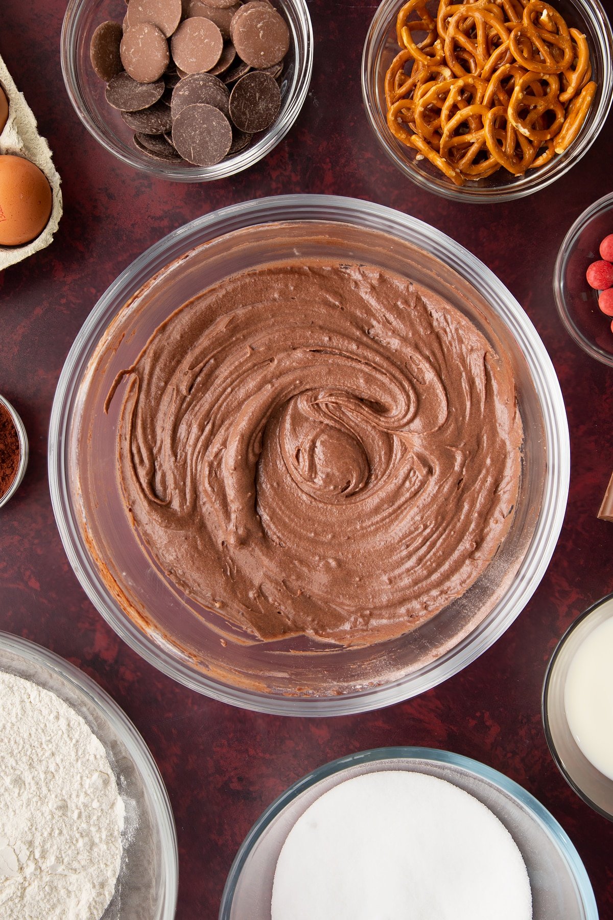 Chocolate cake batter in a bowl. Ingredients to make reindeer cupcakes surround the bowl.