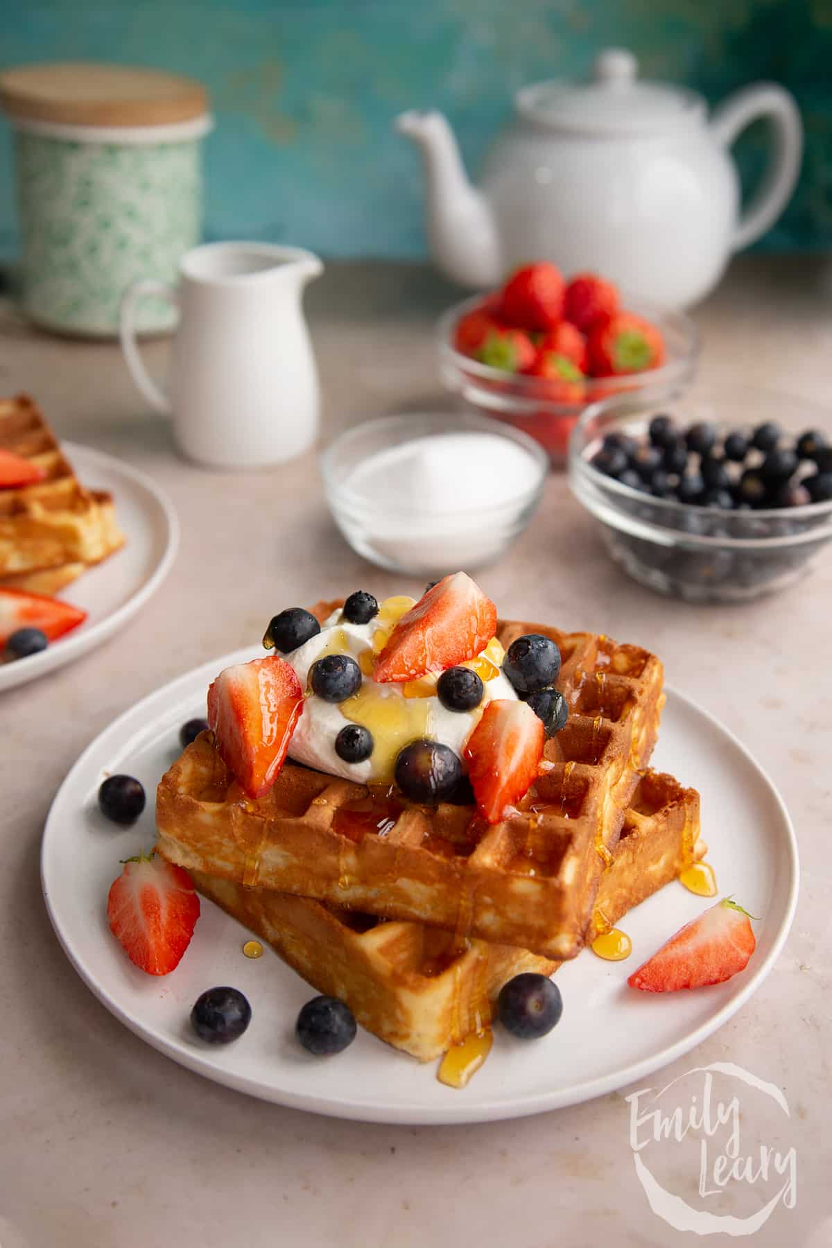 Classic waffles topped with yogurt, honey and berries on a white plate.