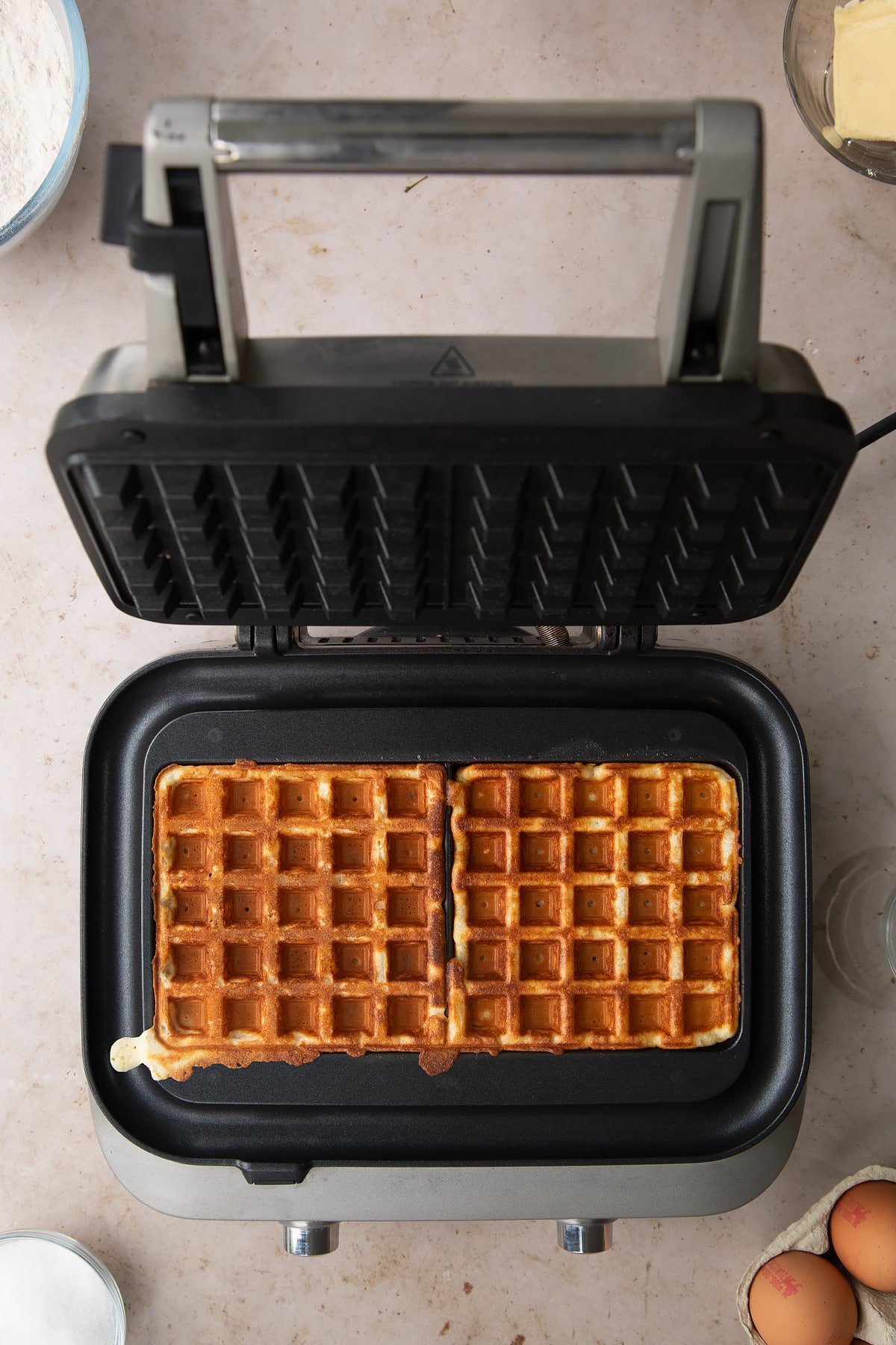 the sage smart waffle maker with two cooked waffles inside.