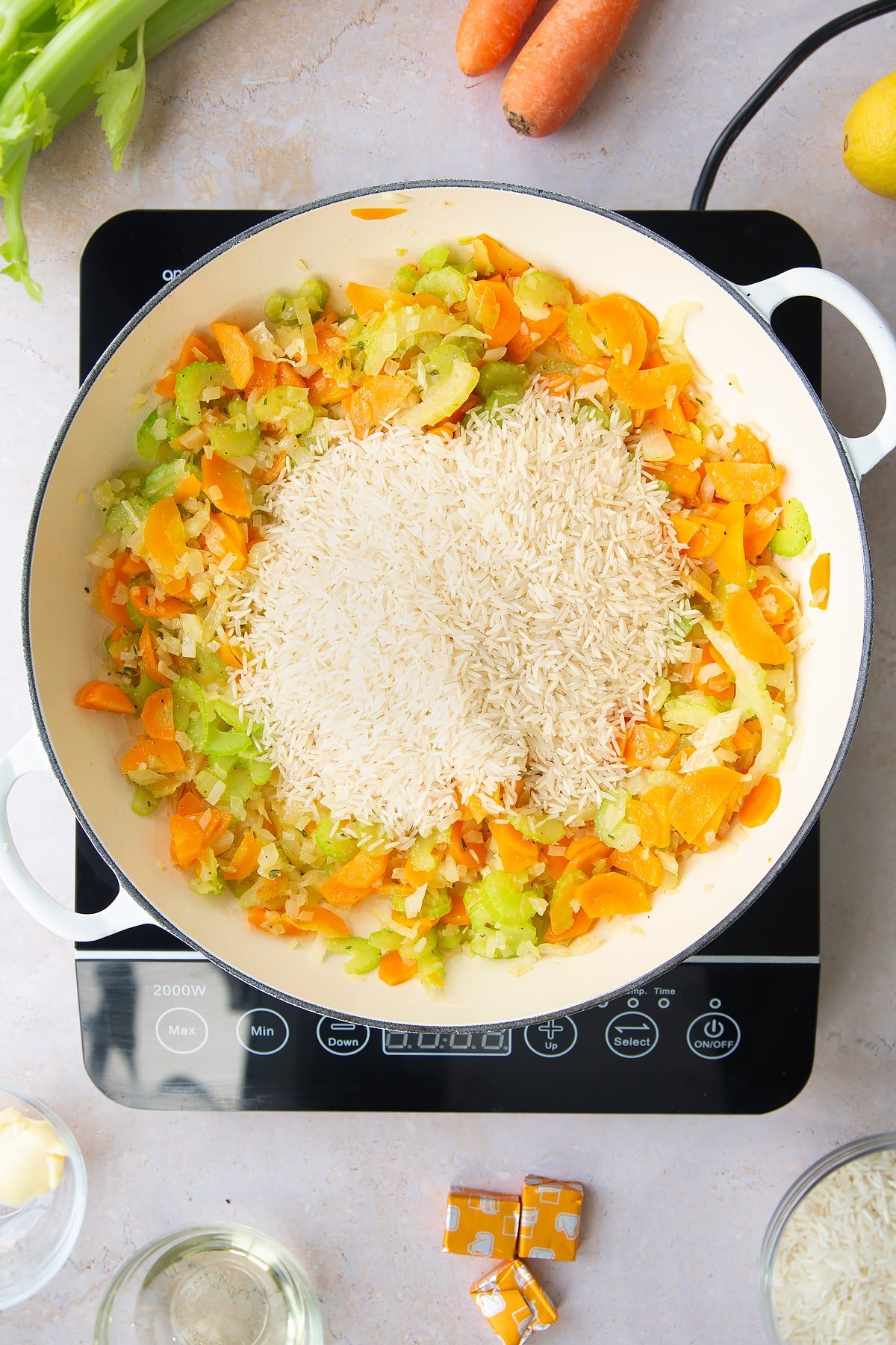 Overhead shot of the rice being added to the top of the vegetables on the hob.