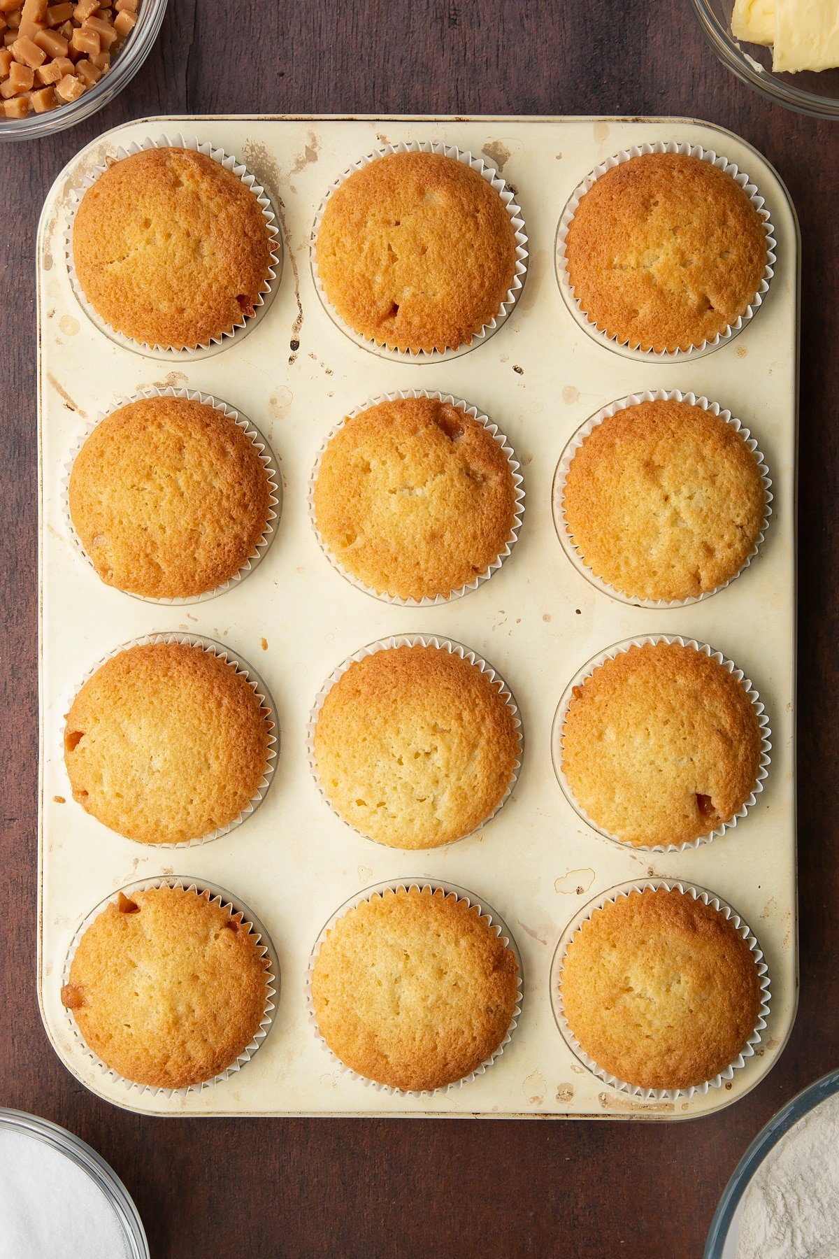 12 baked vanilla fudge chip cupcakes in a bun tray.