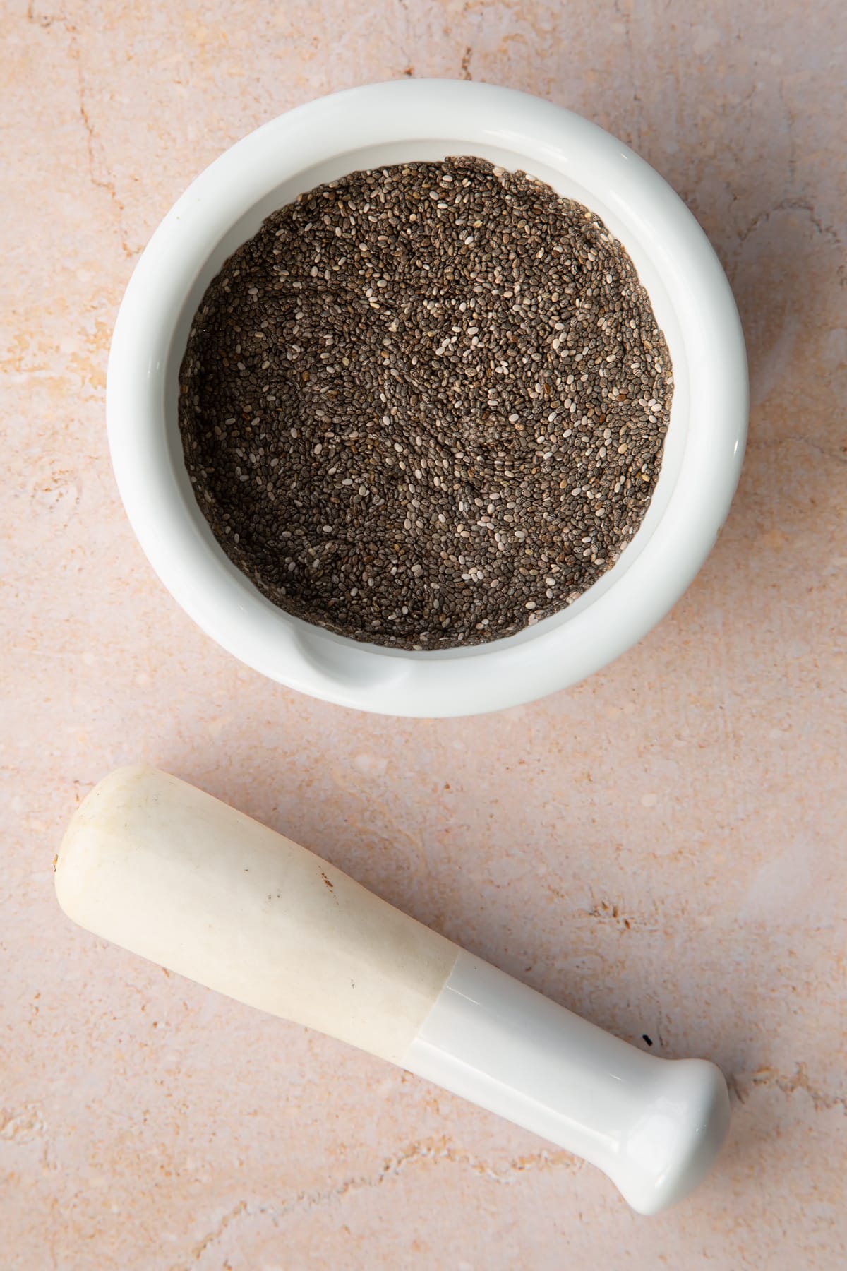 Chia seeds in a mortar with a pestle.
