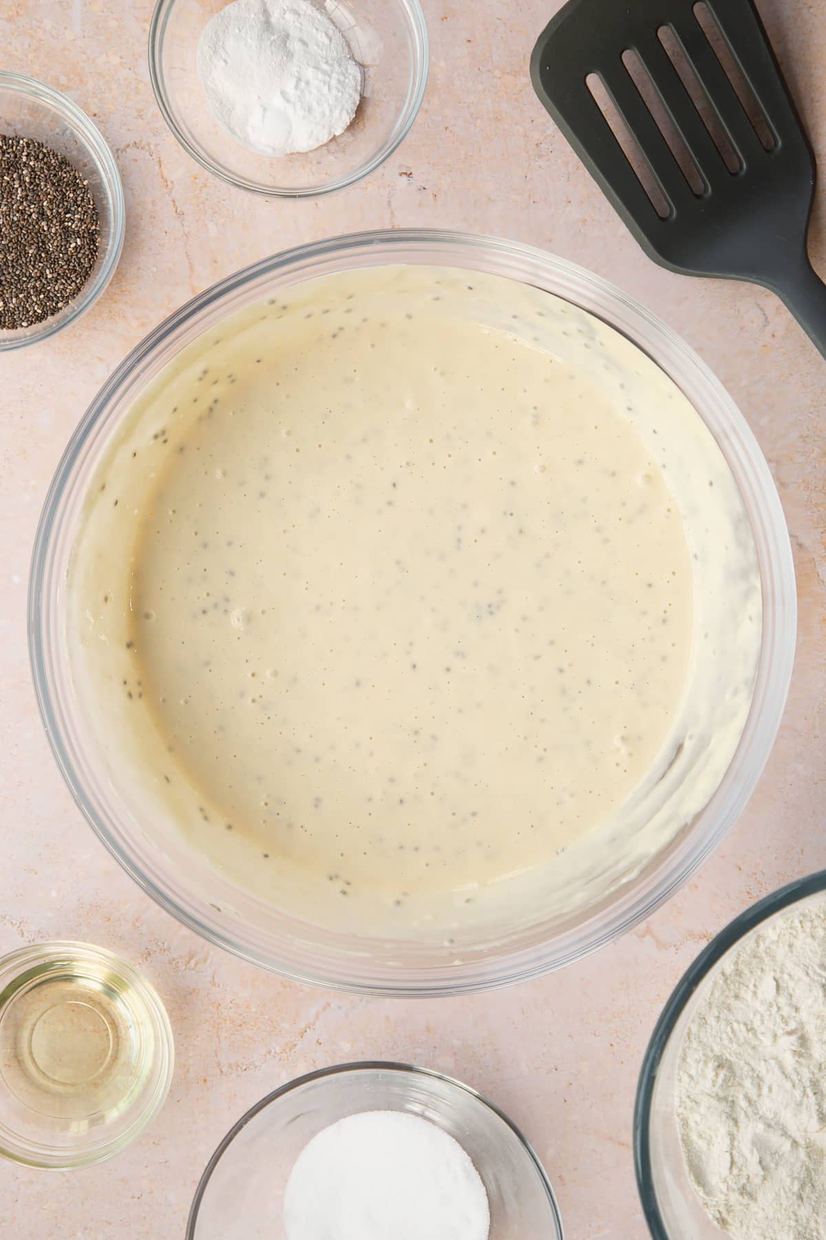 Vegan chia pancakes in a bowl. Ingredients to make vegan chia pancakes surround the bowl.