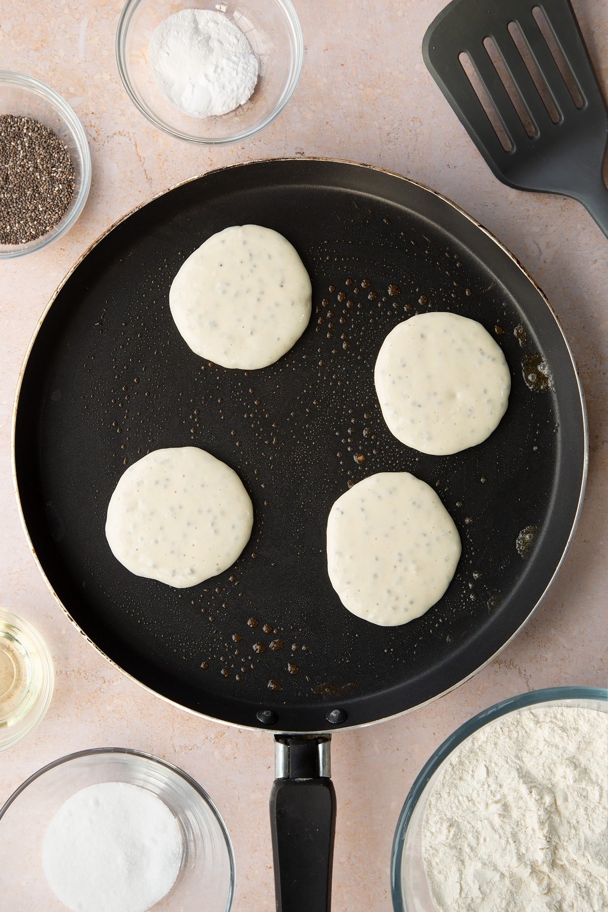 A pancake pan with four spoonfuls of vegan chia pancake batter.