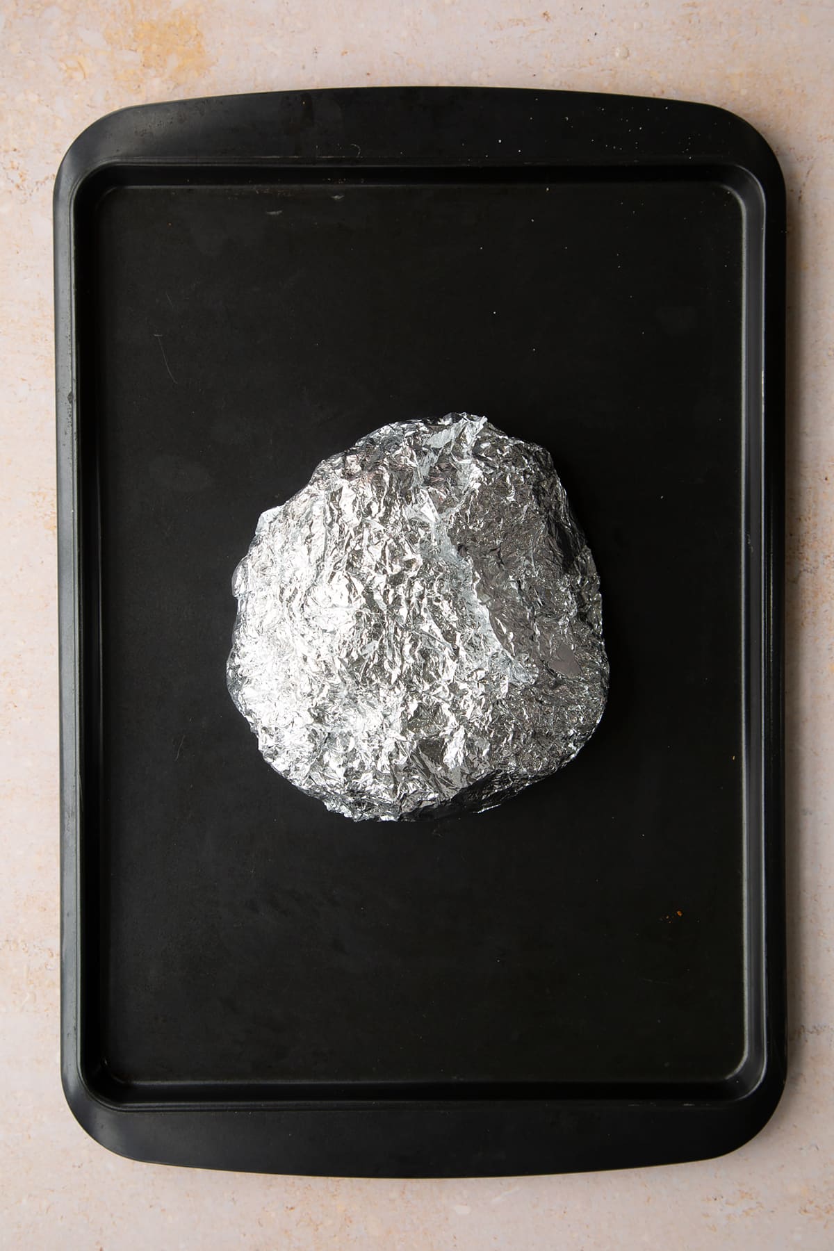 A paper and foil packet on a baking tray.