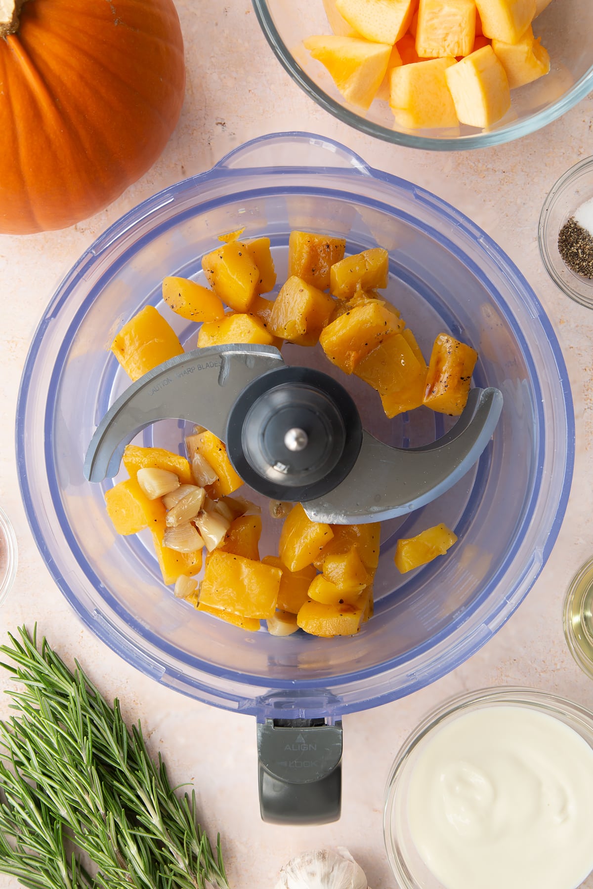 Roasted pumpkin and garlic in a food processor bowl.