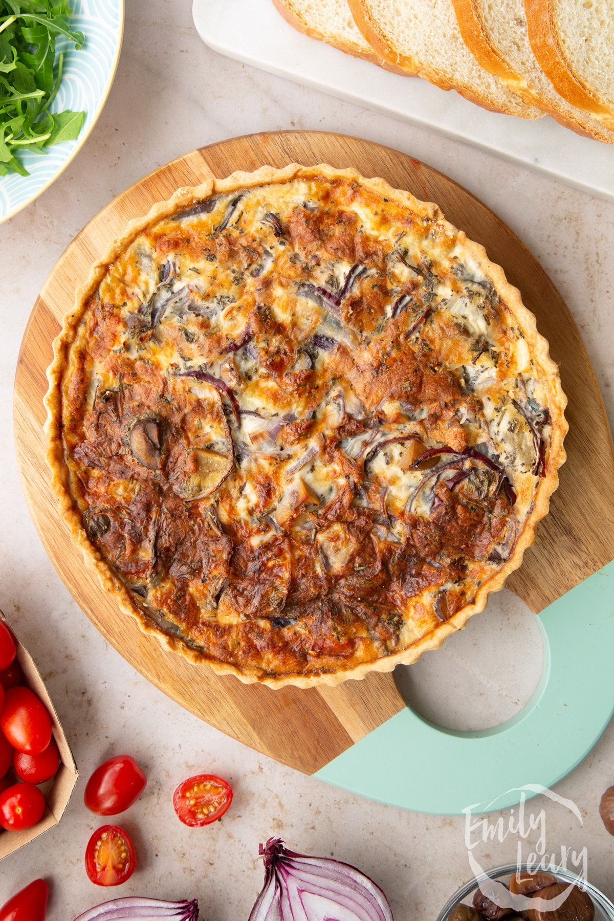 Overhead shot of the finished chestnut quiche on a decorative wooden chopping board.