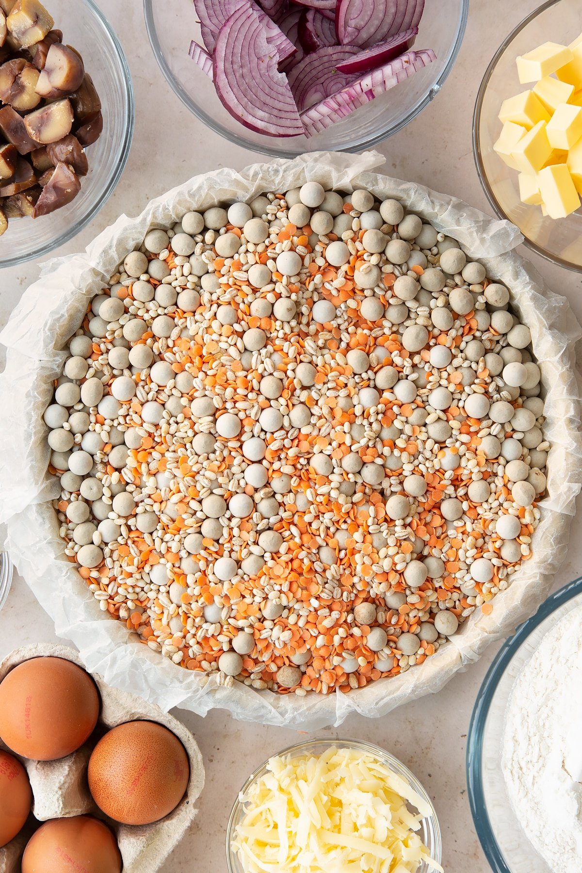 Overhead shot of the pastry inside the pie tin being worked in with baking beans. 