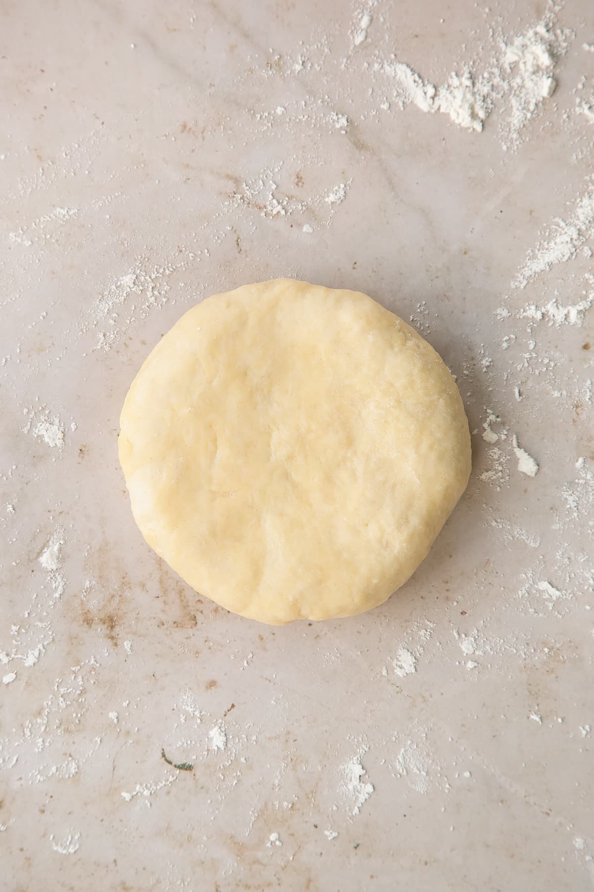 Overhead shot of the flattened pastry mixture on a lightly floured surface.